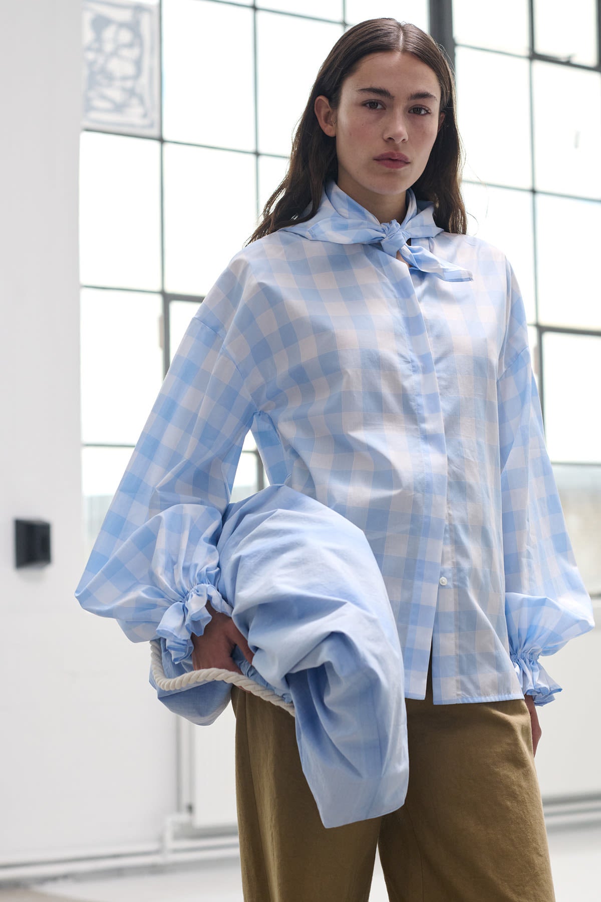 Model wearing Heather blue check blouse with puffed sleeves, styled with tailored cuffs.