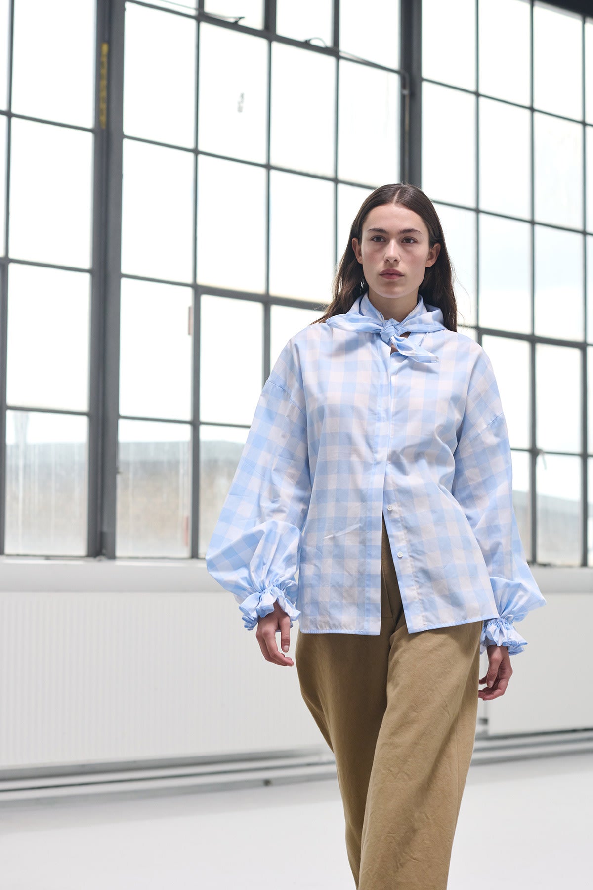 Model wearing Heather blue check blouse with puffed sleeves, styled with tailored cuffs.