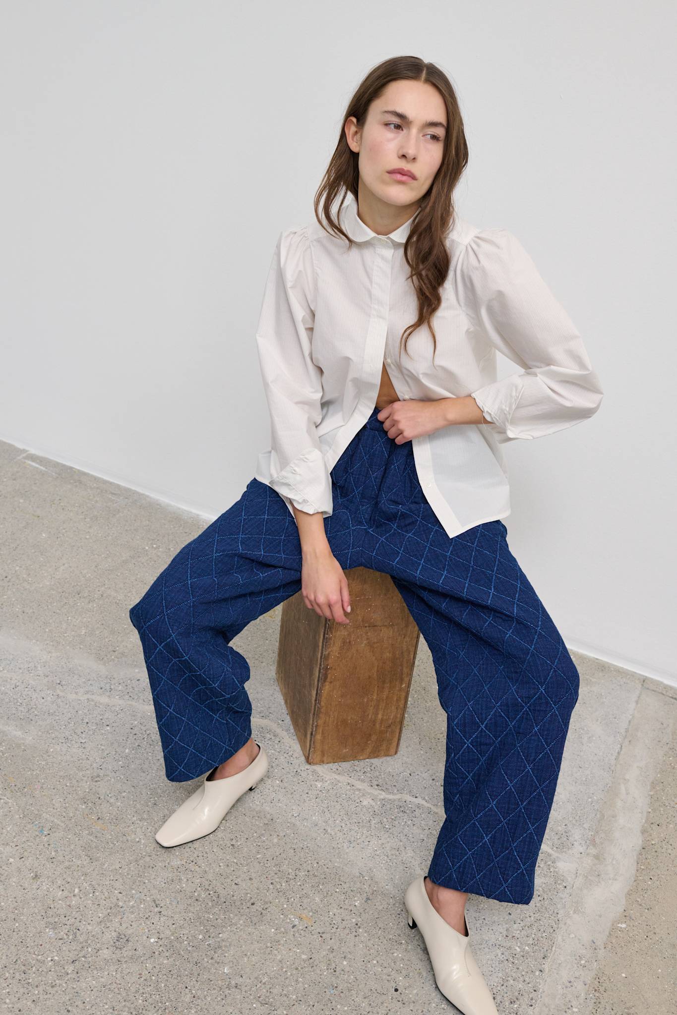 Model wearing the Patricia Shirt, a white striped button-up shirt with a relaxed fit.