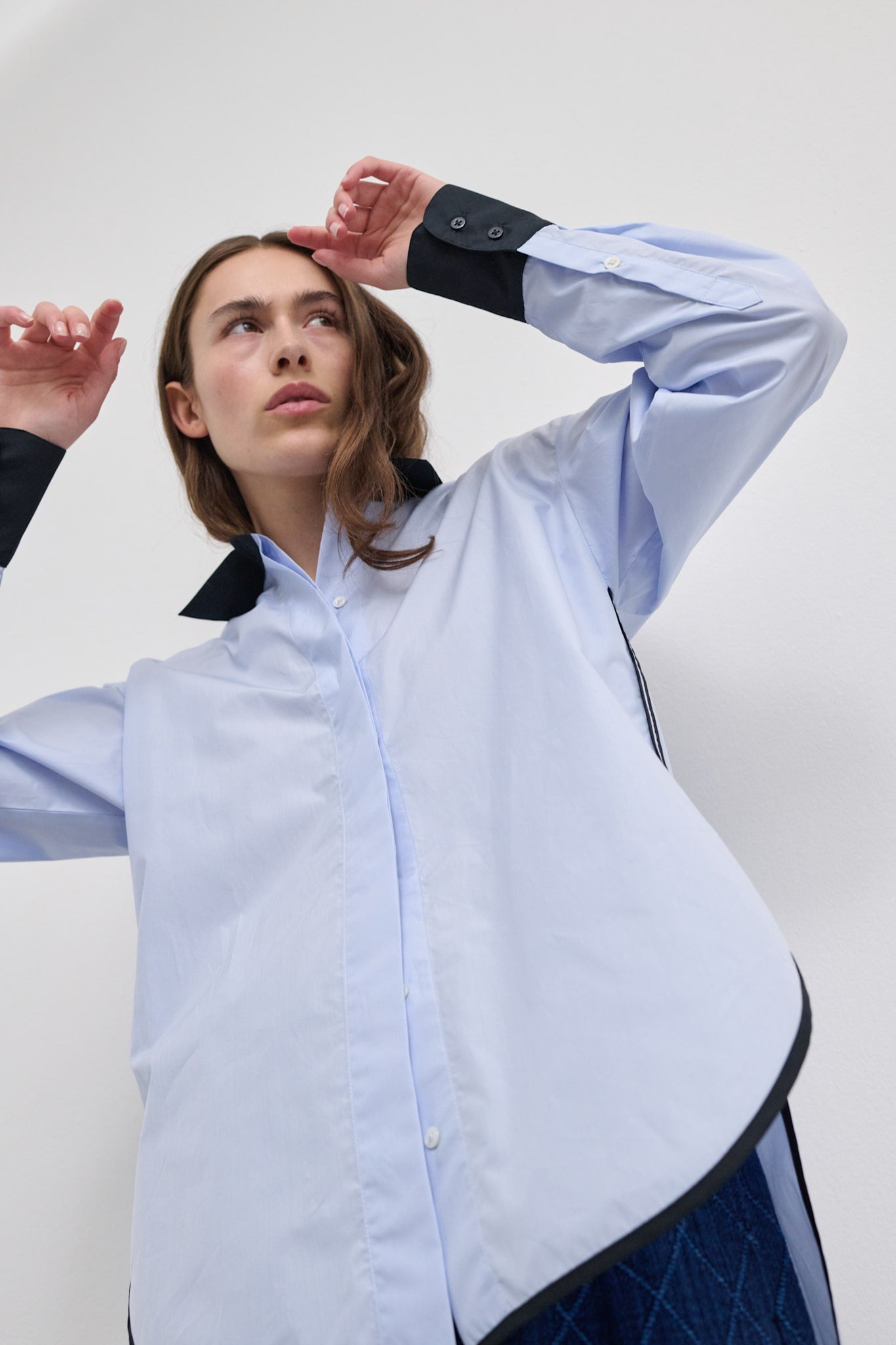 Model adjusting the sleeve of the Vega contrast collar shirt, showing the elongated cuff with fold-back styling.