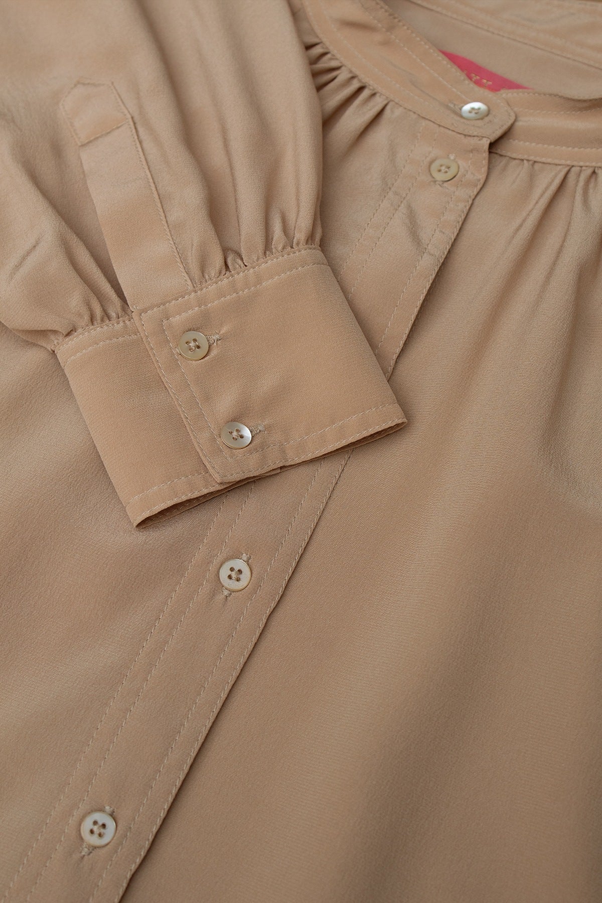 Close-up of the silk blouse’s cuff, showcasing the classic buttoned closure and elegant draping.