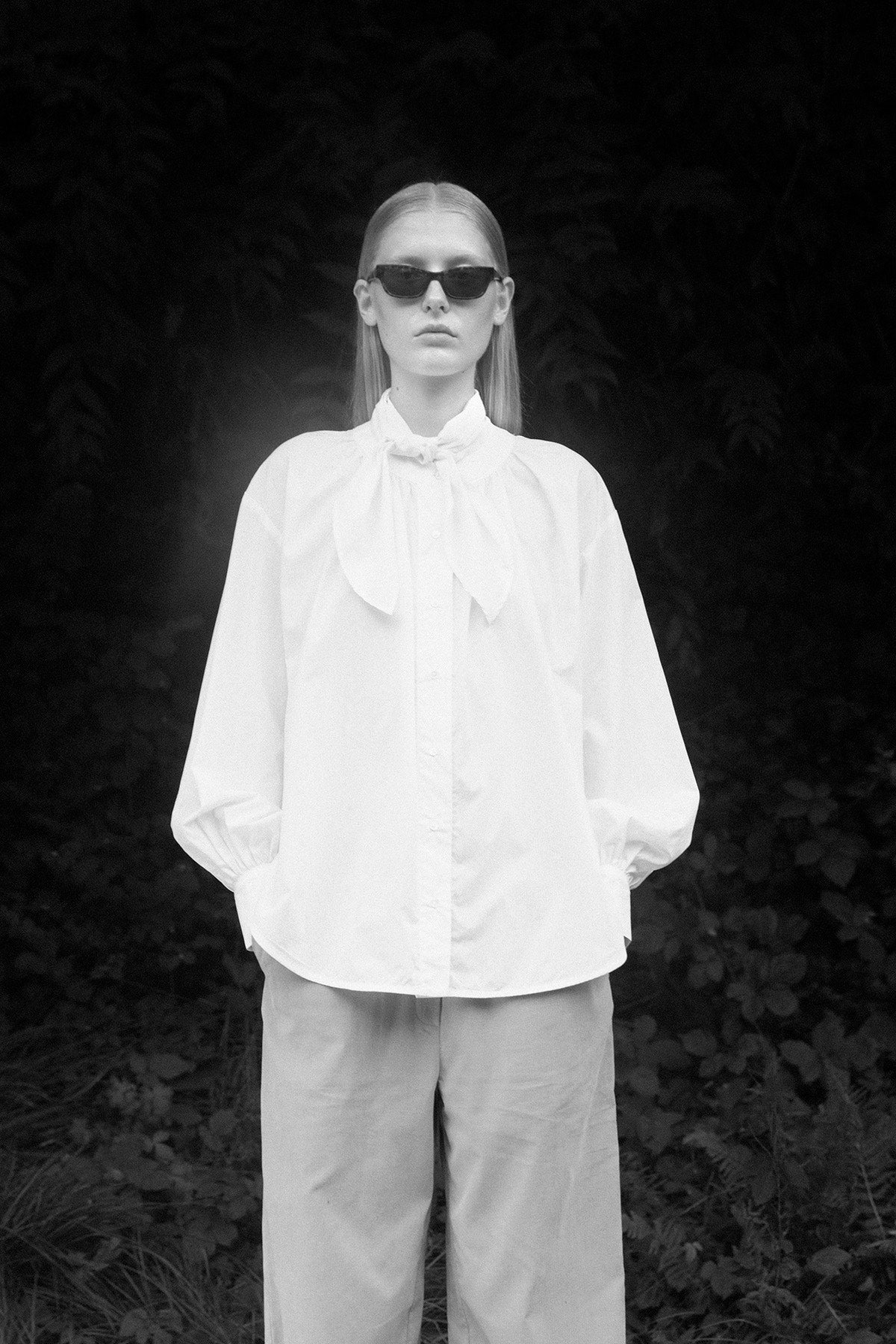 Full-body shot of a model in the white cotton shirt, highlighting the flowy sleeves and statement tie.