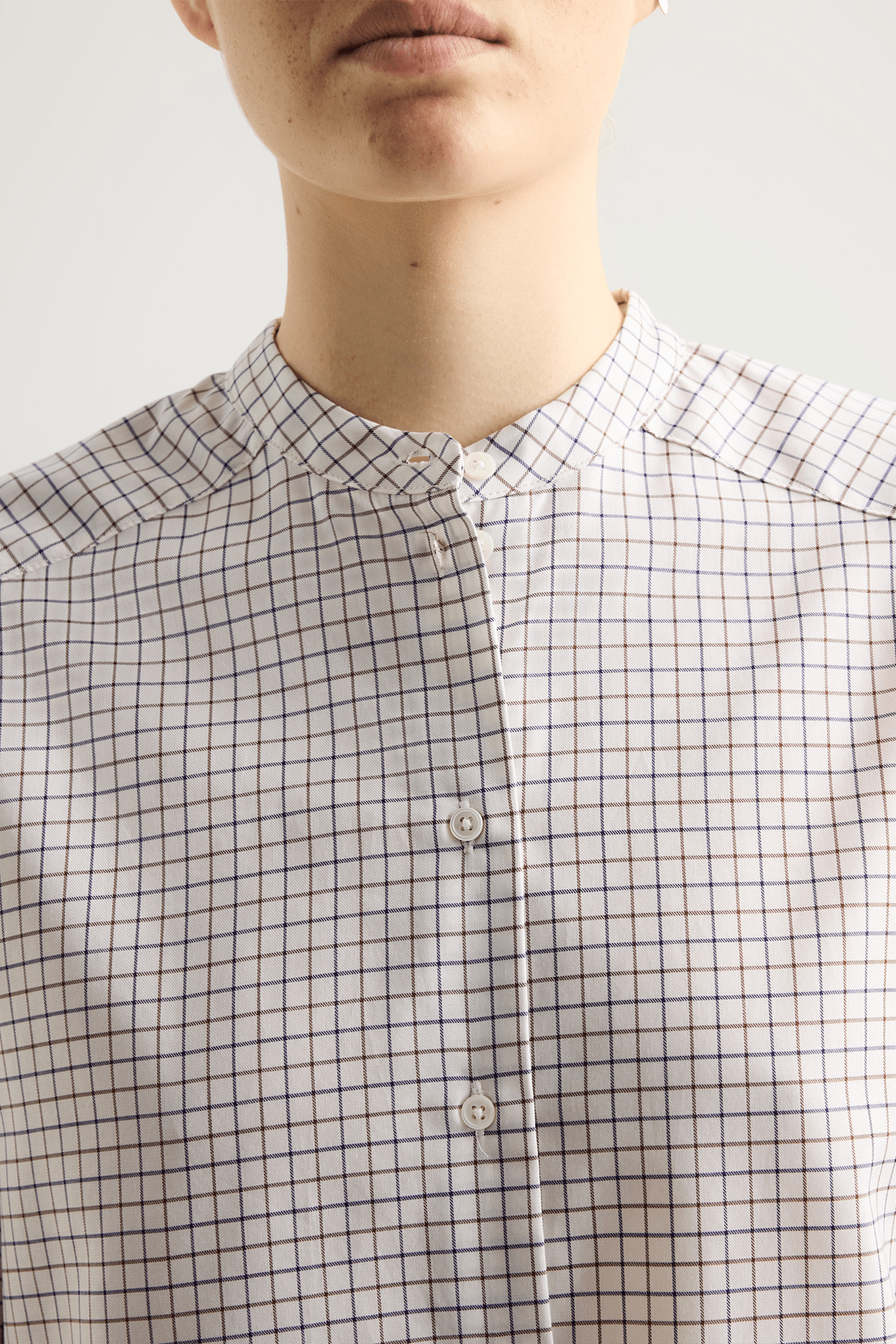 Model wearing Bea shirt with straight silhouette, stand collar and raw-edge sleeves.