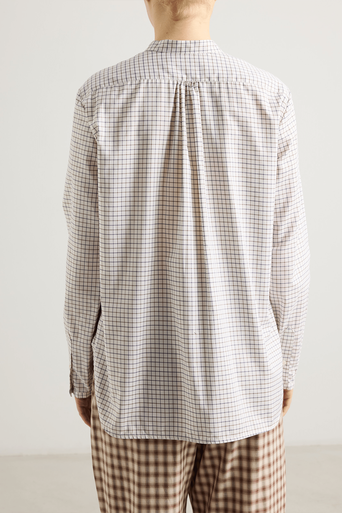 Model wearing Bea shirt with straight silhouette, stand collar and raw-edge sleeves.