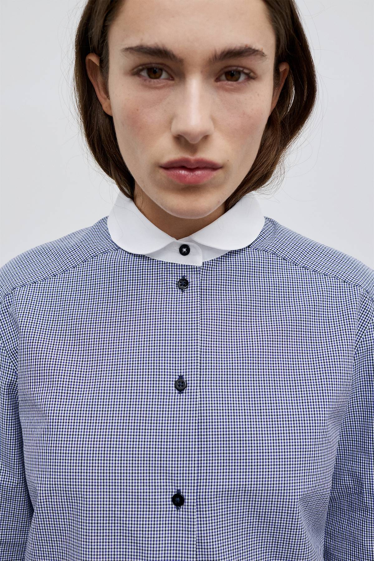 Close up to the model in Bonnie Shirt – Blue checkered shirt with Peter Pan collar and black button-up front.