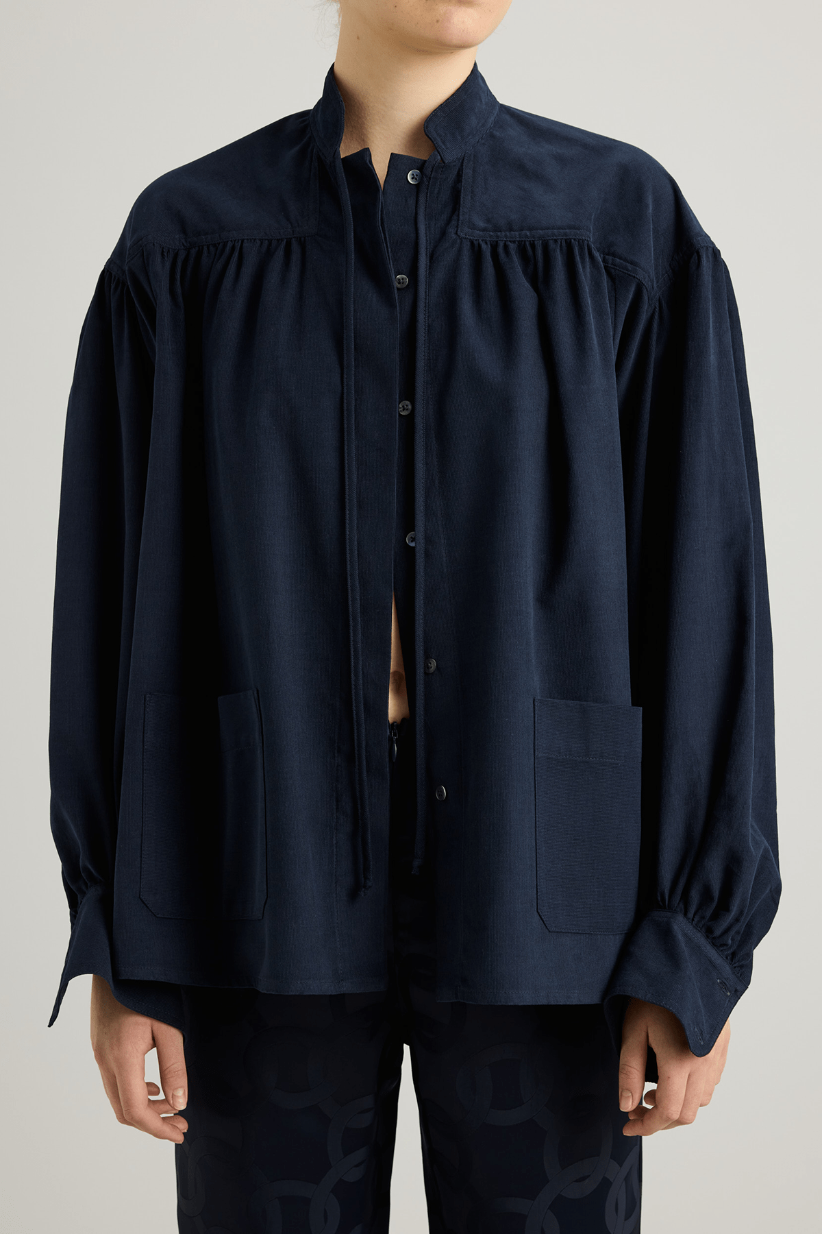Navy shirt with a tie-neck detail, front button closure, and long voluminous balloon sleeves gathered at the wrists.