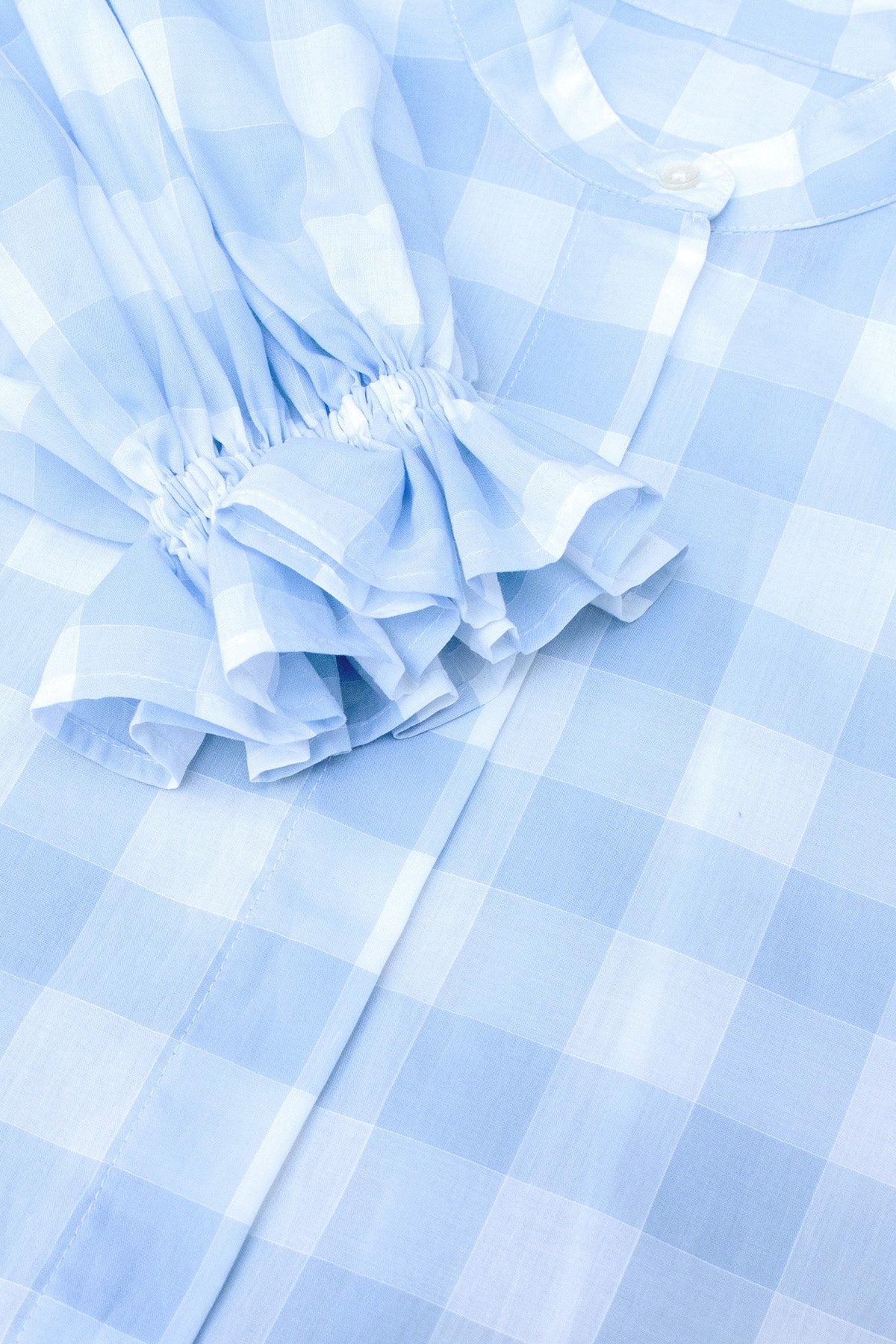 Side view of Heather blue check blouse with puffed sleeves, showcasing the structured silhouette.