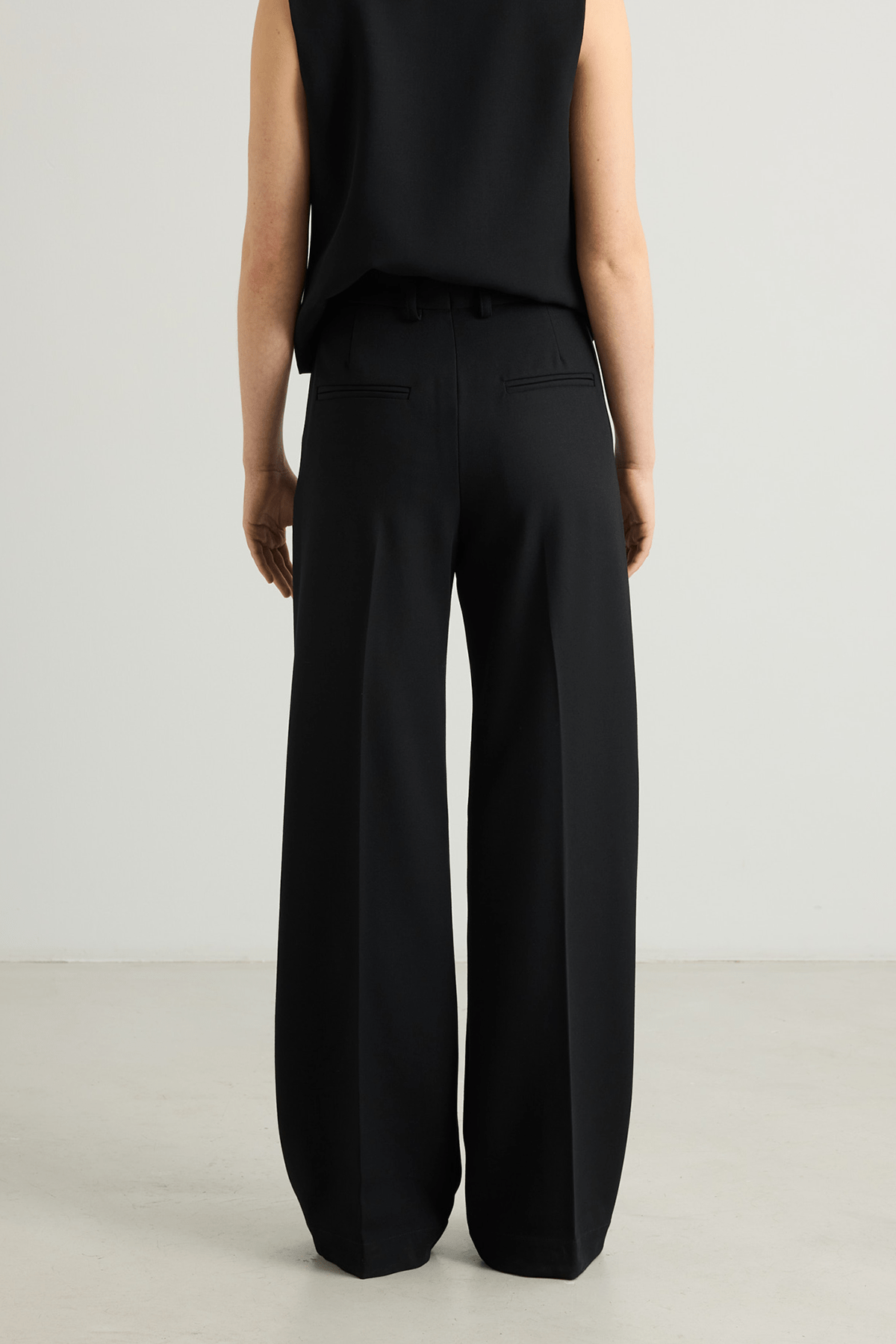 Model wearing Kosta trousers in black wool suiting with structured wide leg.