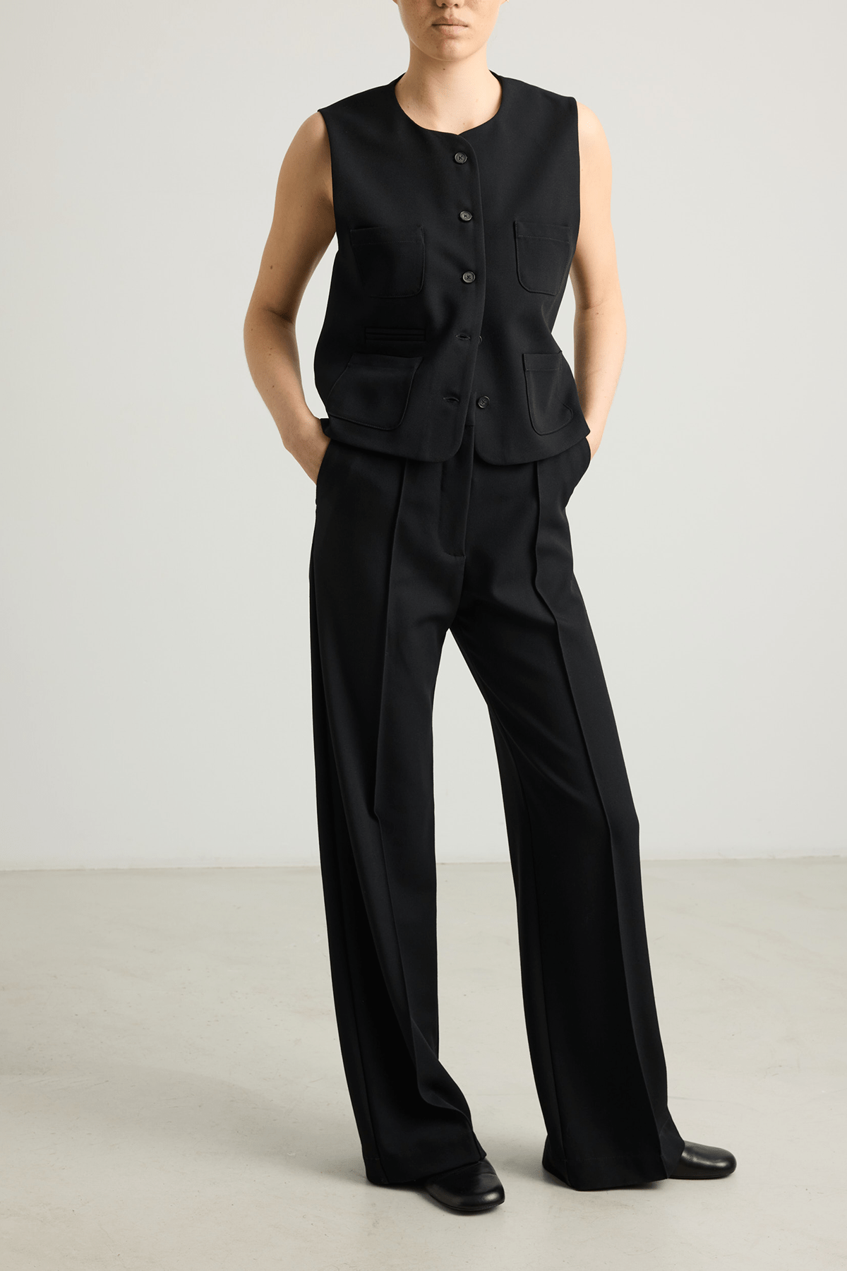 Model wearing Kosta trousers in black wool suiting with structured wide leg.