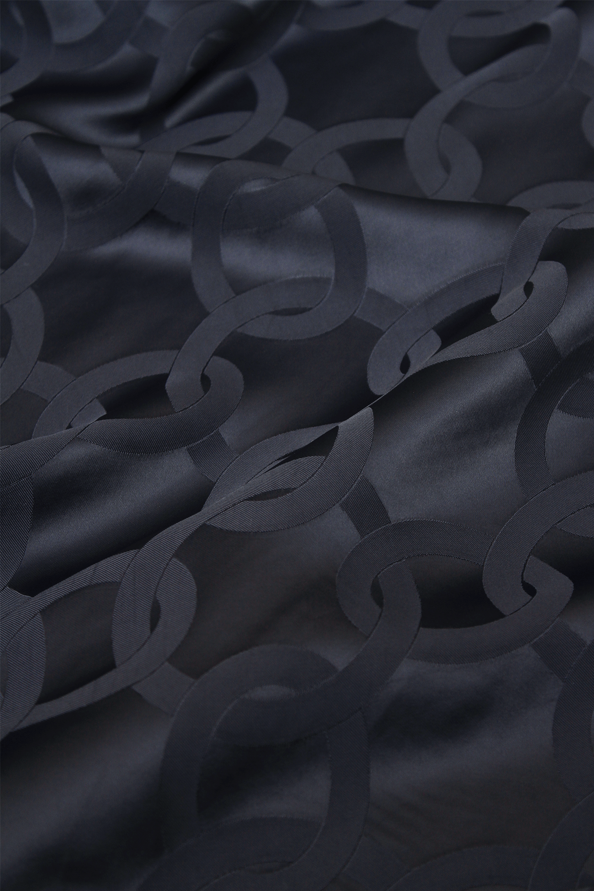 Close-up of Kasey trousers in dark blue satin jacquard with flounced hem.