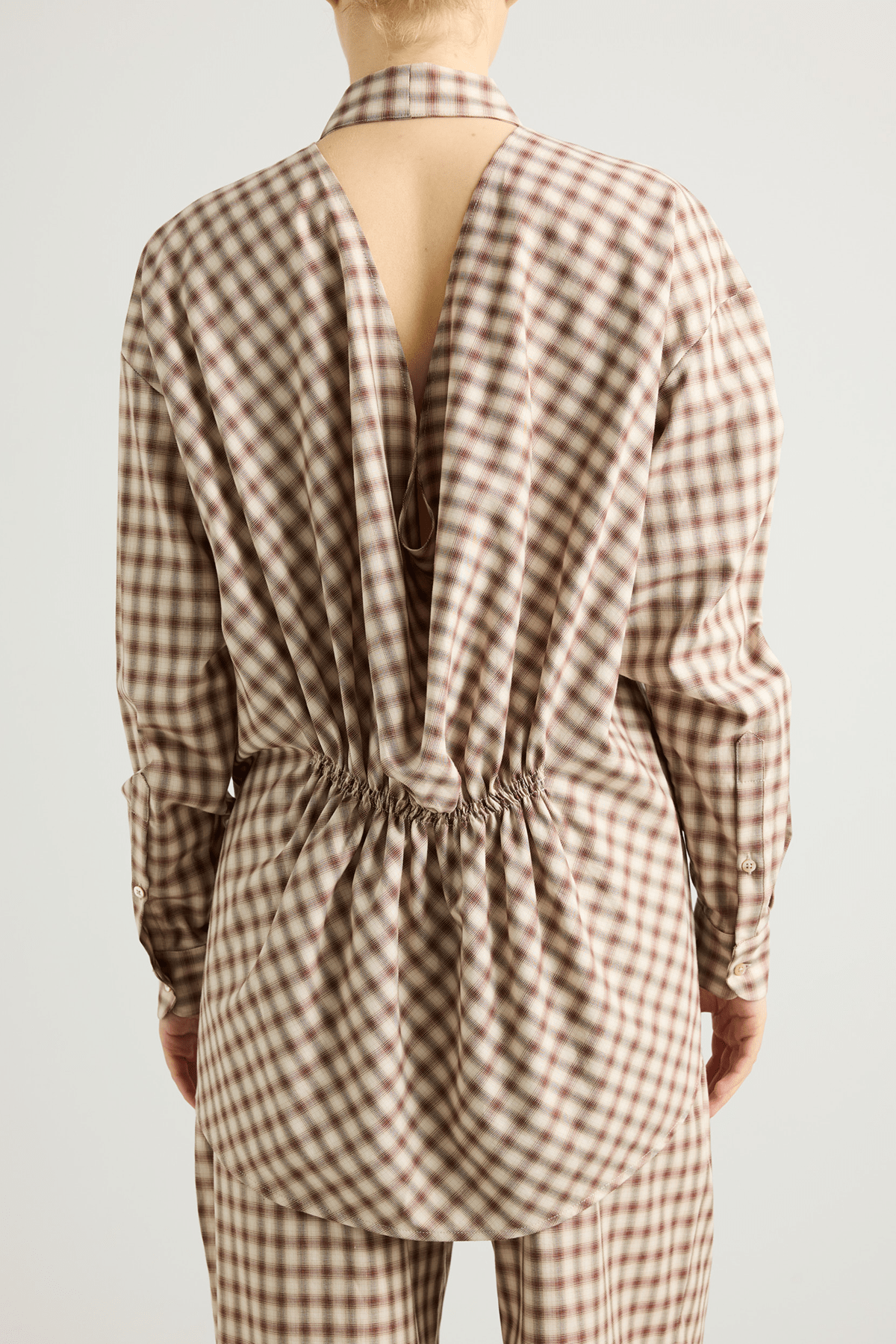 Model wearing the Mina shirt with V-neckline and draped back detail.