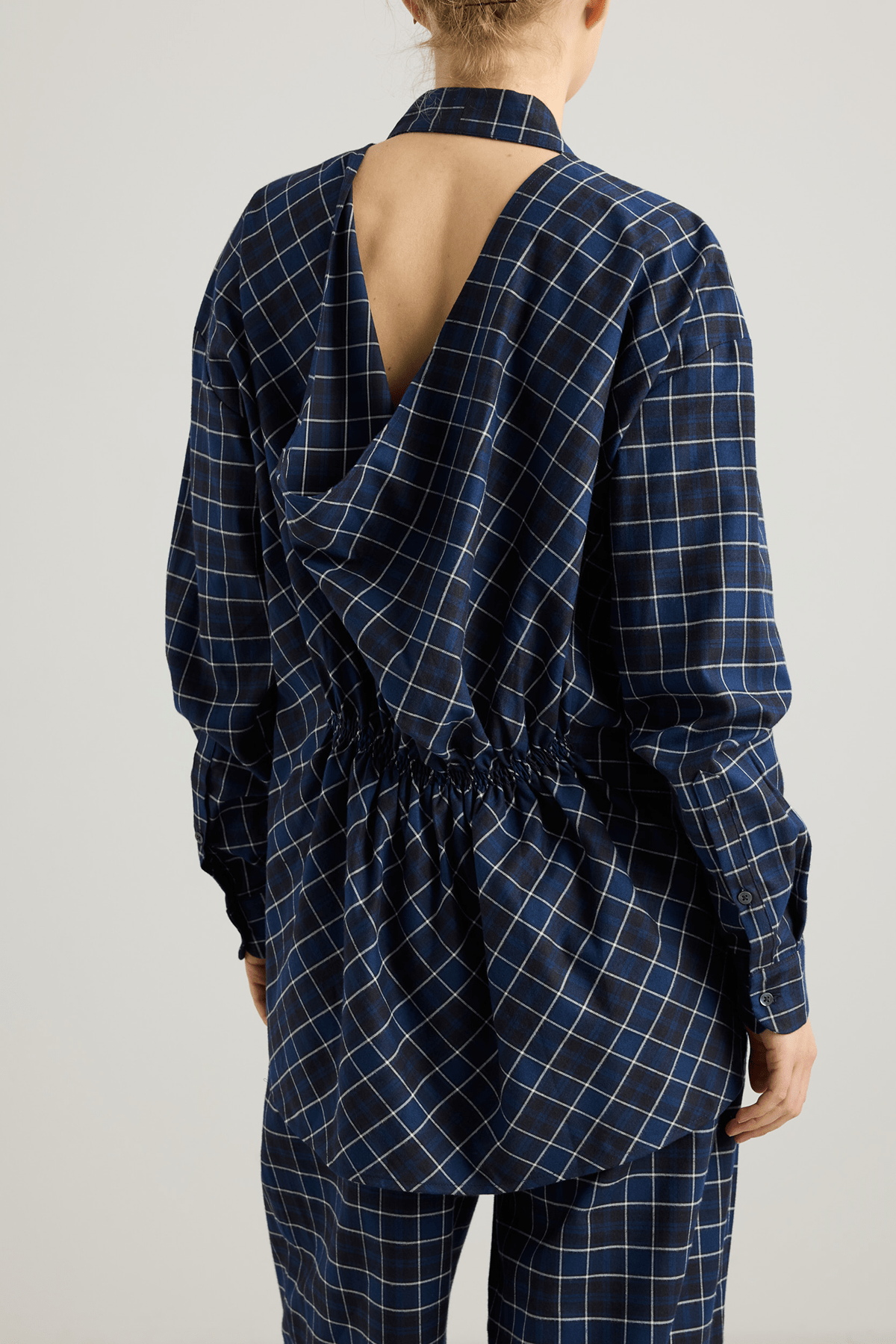 Model wearing the Mina shirt with V-neckline and draped back detail.