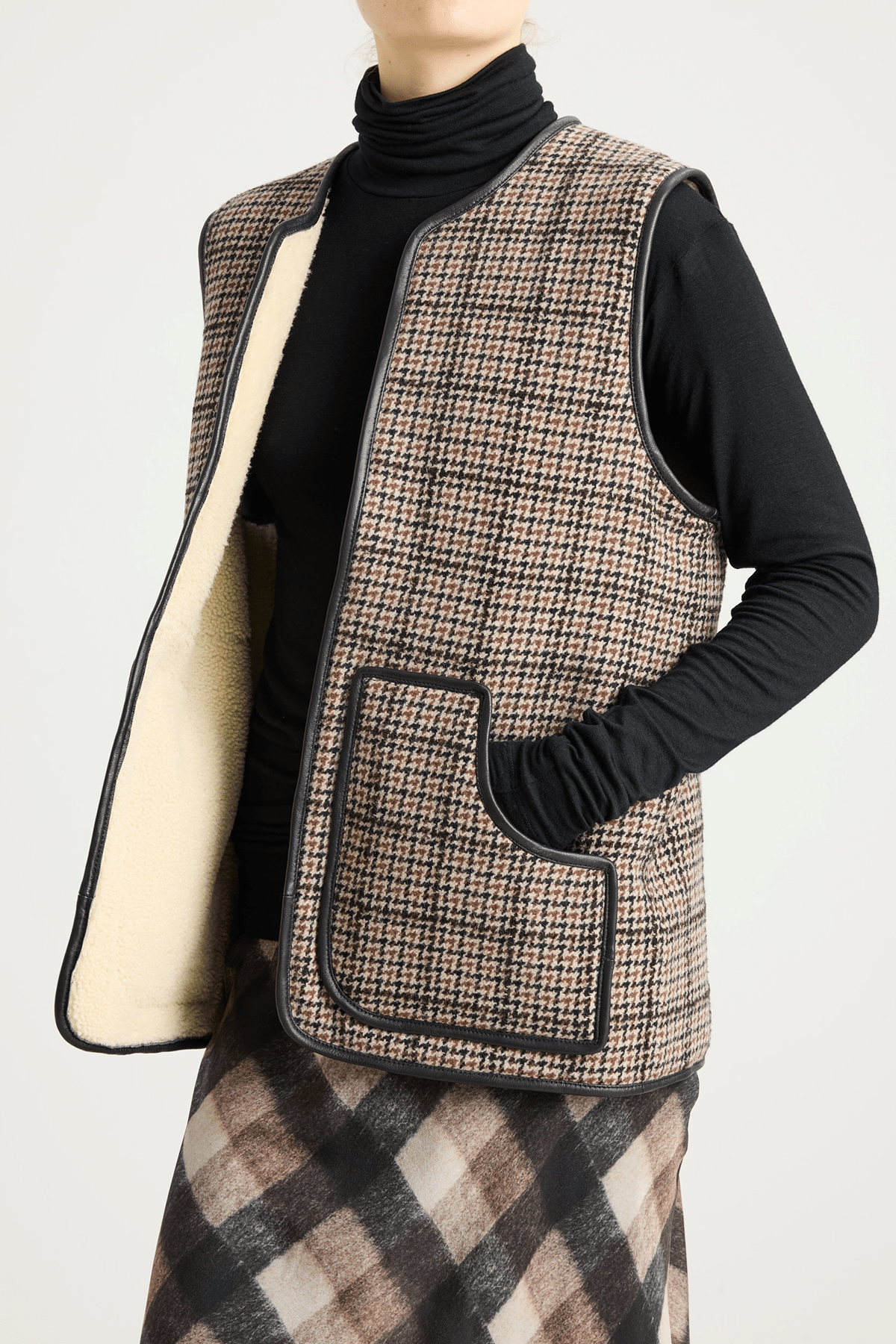 Model wearing shearling-lined winter vest in brown check lambswool and leather.