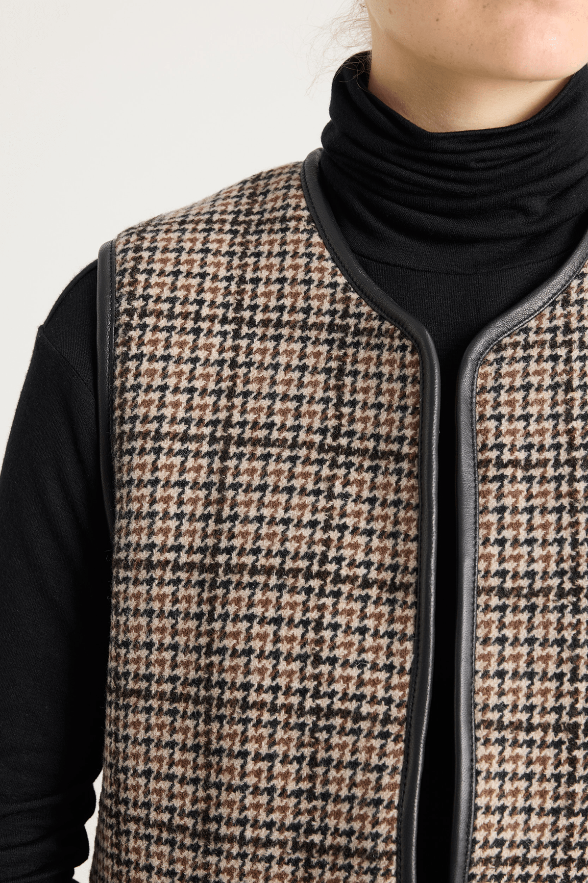 Model wearing shearling-lined winter vest in brown check lambswool and leather.