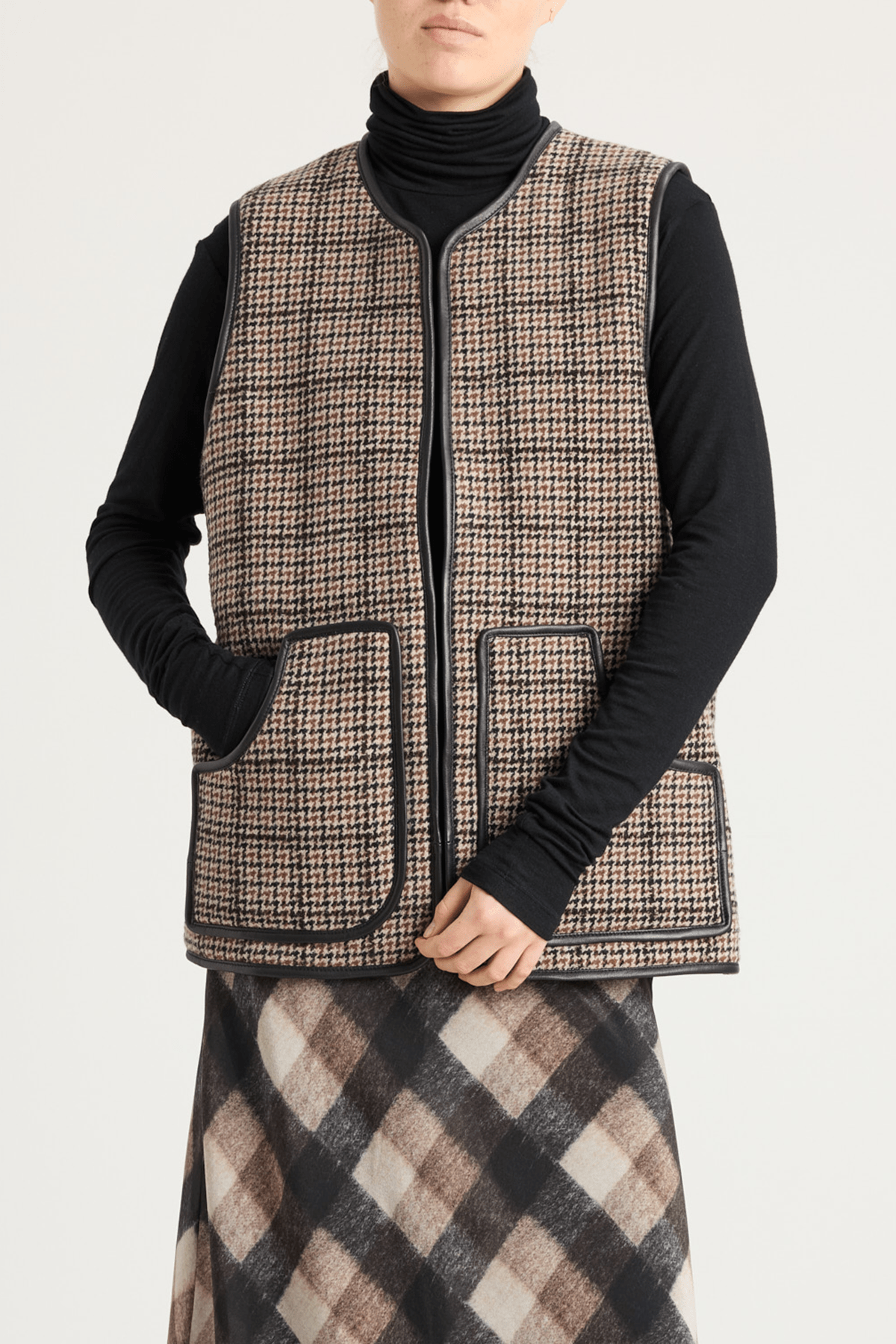Model wearing shearling-lined winter vest in brown check lambswool and leather.
