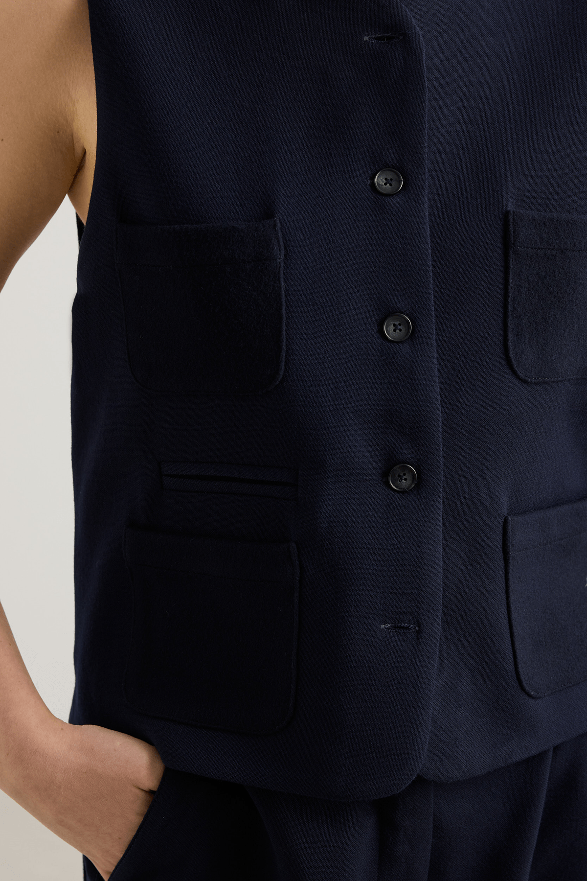Model wearing dark blue Tinnie vest in cashmere–virgin wool with cropped silhouette and contrast pockets.