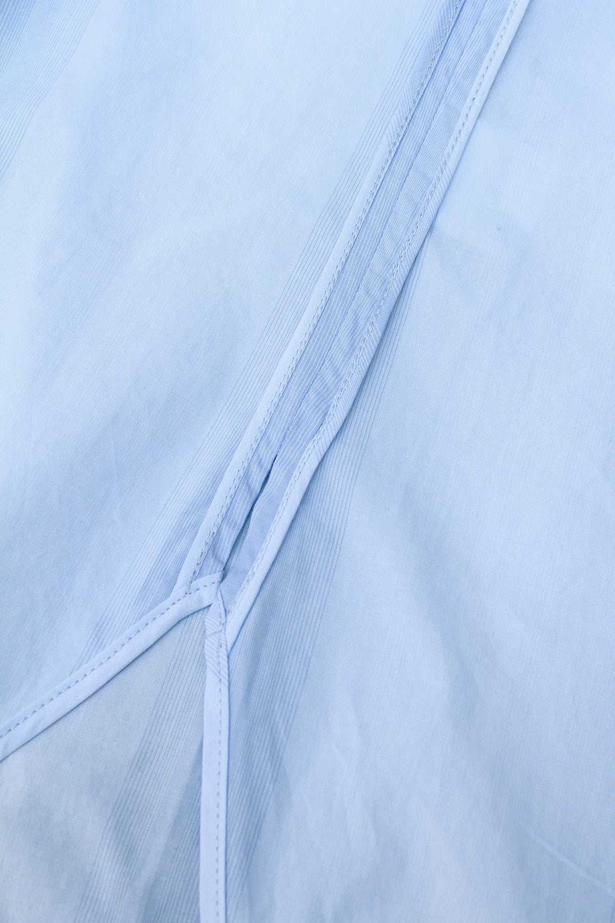 Detail shot of the shirt’s classic collar and button closure in blue gradient striped cotton.