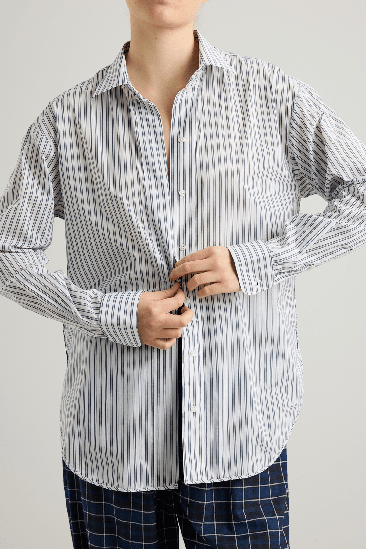 Model wearing Vega shirt in white cotton with grey stripes and elongated cuffs.