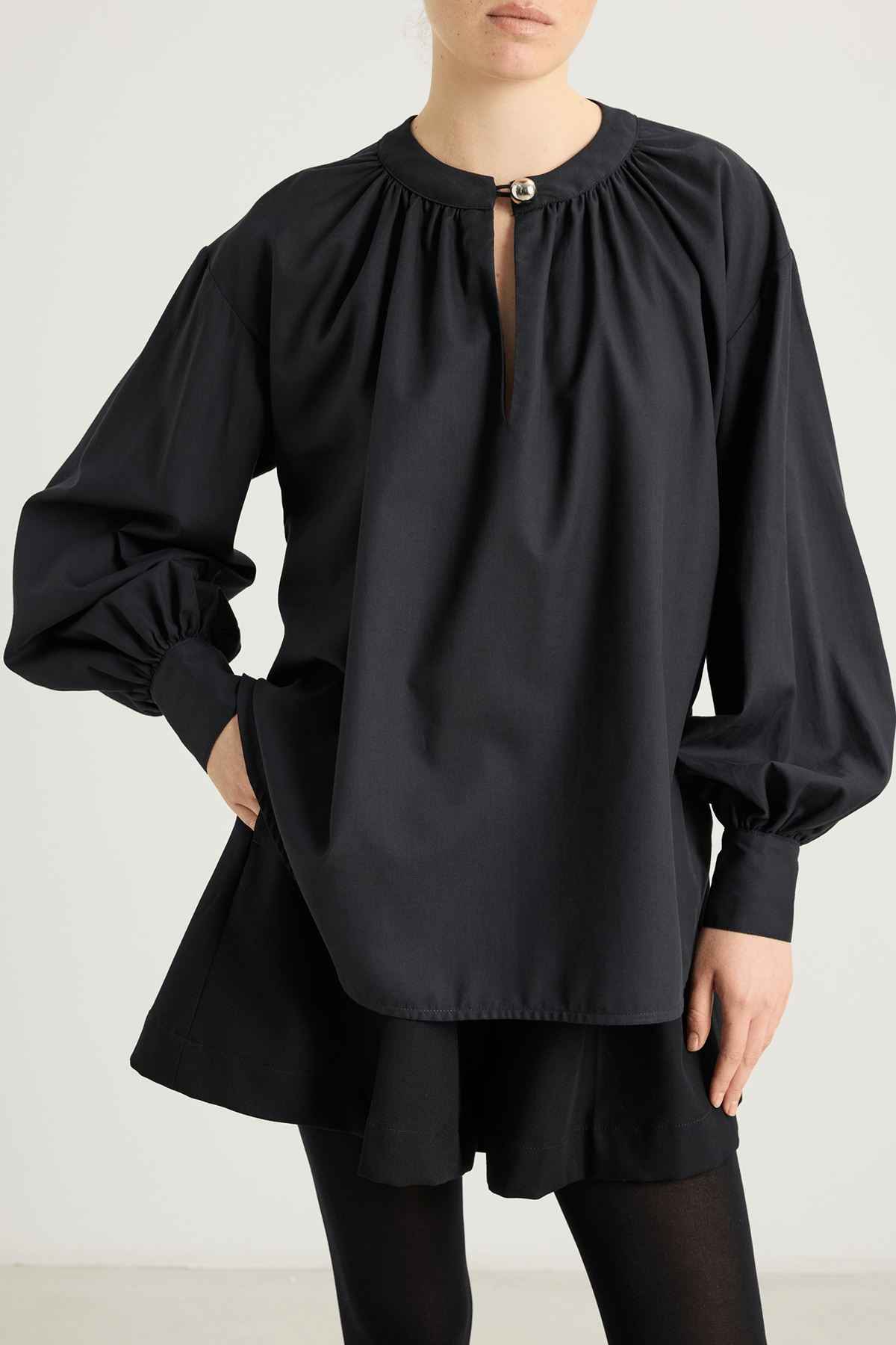 Model wearing Veronica black voluminous shirt with gathered neck and cuffs.