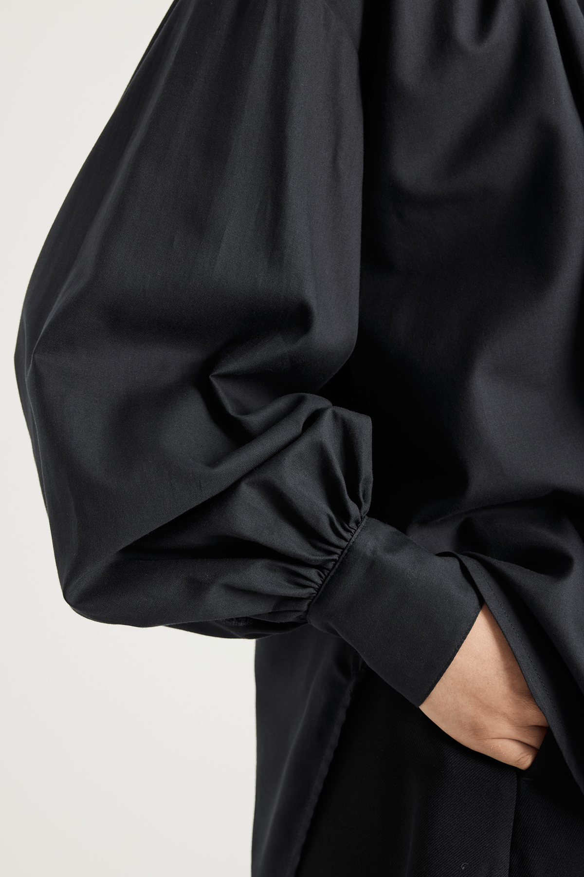 Model wearing Veronica black voluminous shirt with gathered neck and cuffs.