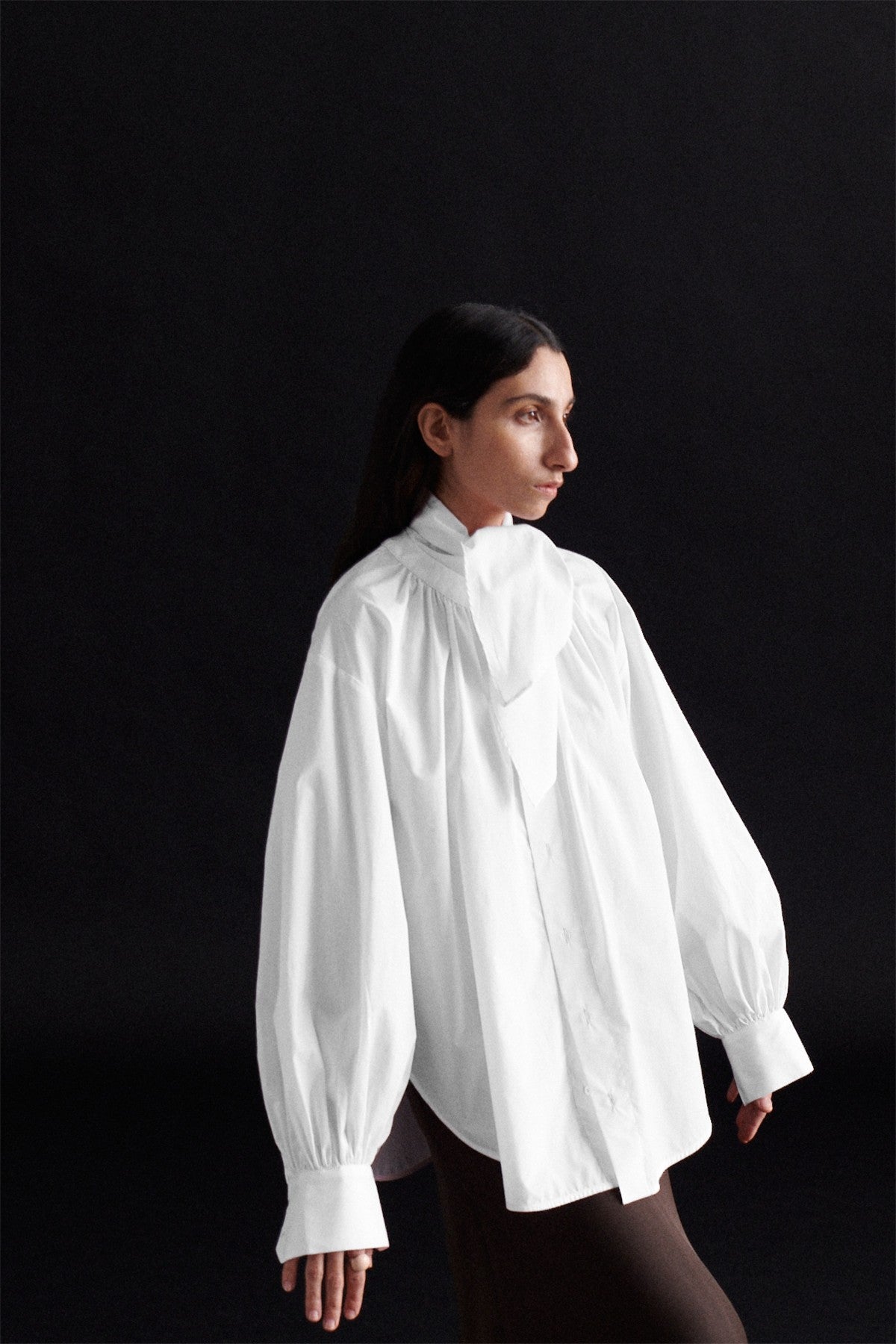 Editorial shot of the white tie shirt, showcasing its structured collar and delicate fabric.