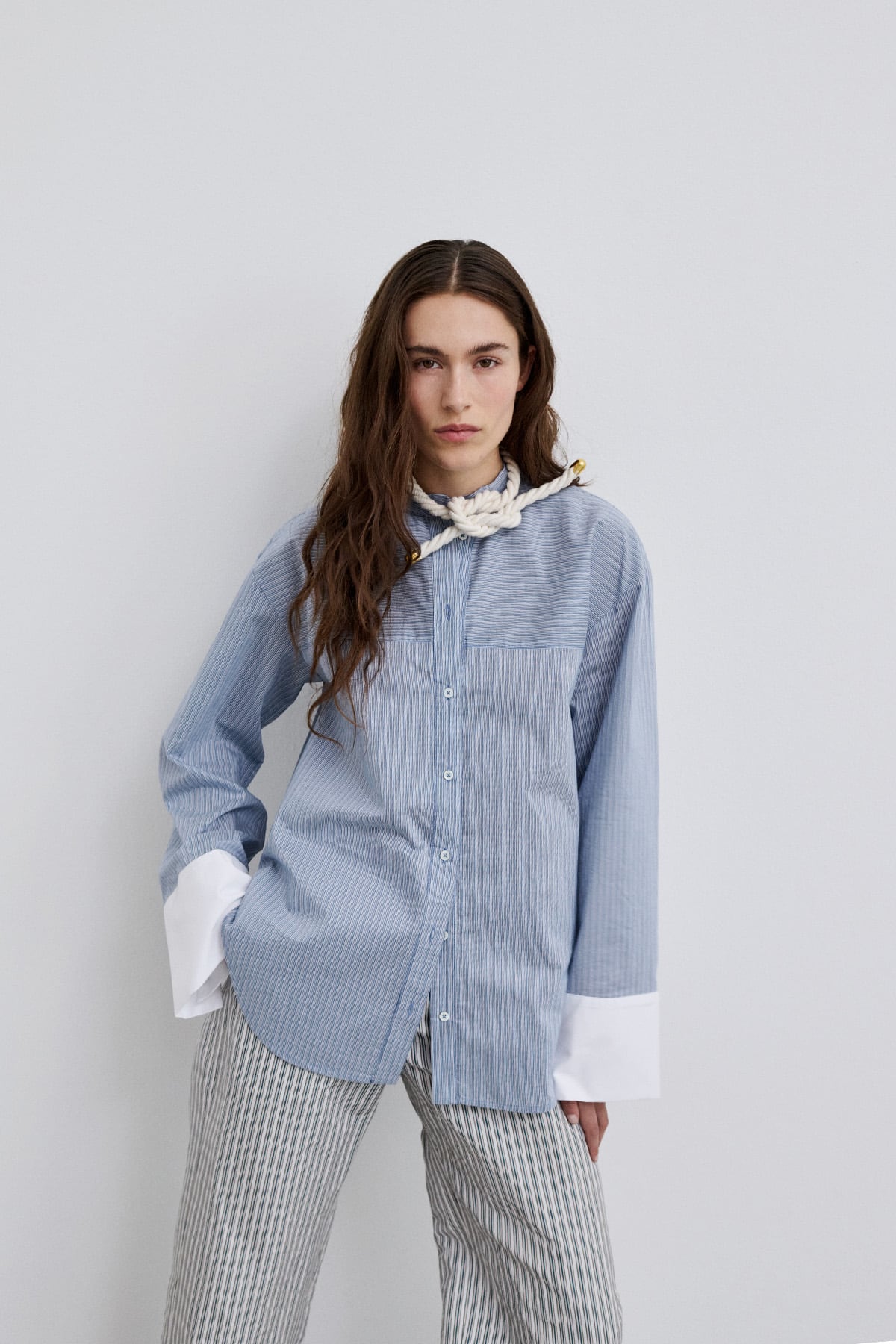 Model wearing Viola blue striped shirt with a blouse with wide sleeves, showcasing its contrasting cuffs.