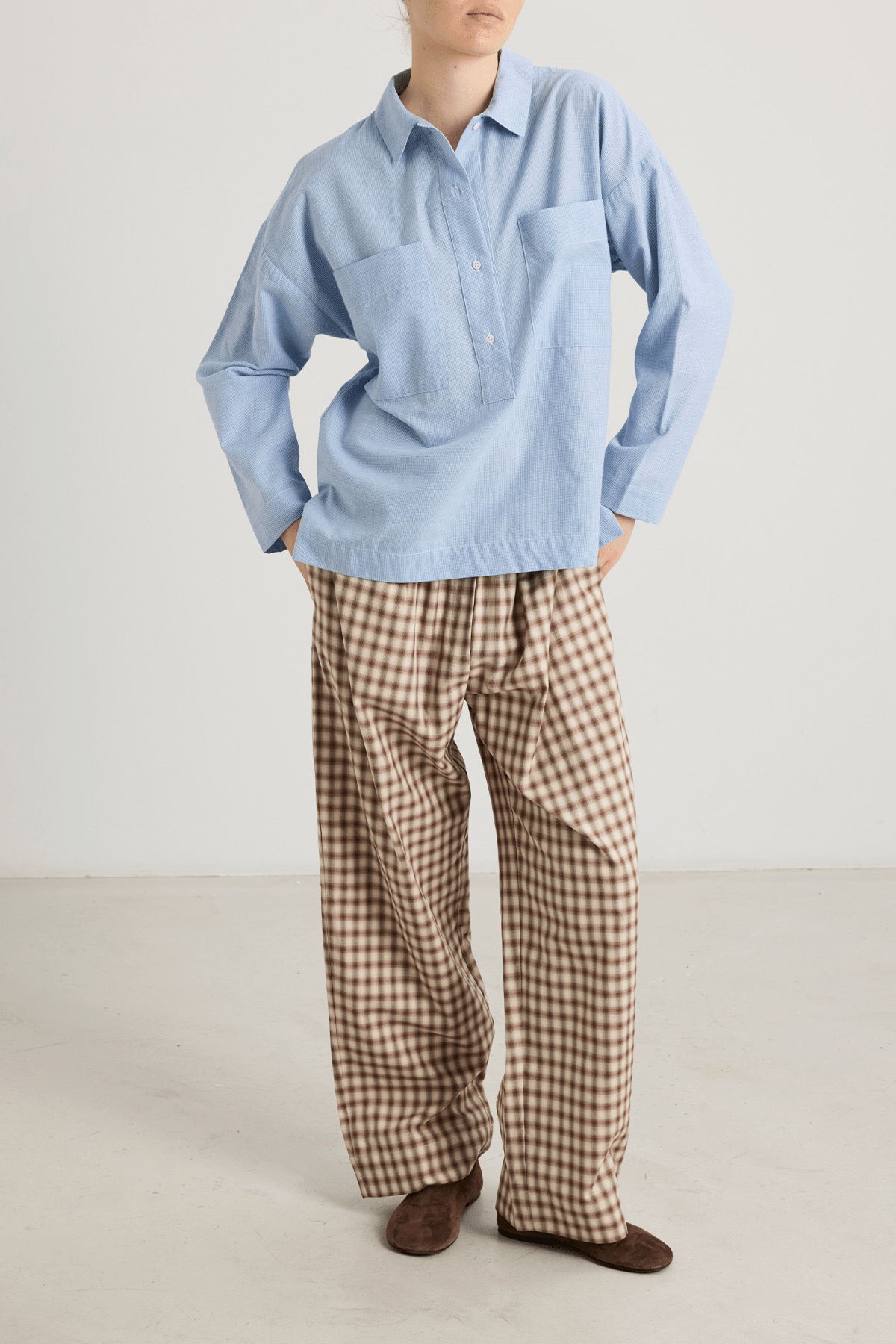 girl wearing blue houndstooth shirt with big pockets and brown check trousers