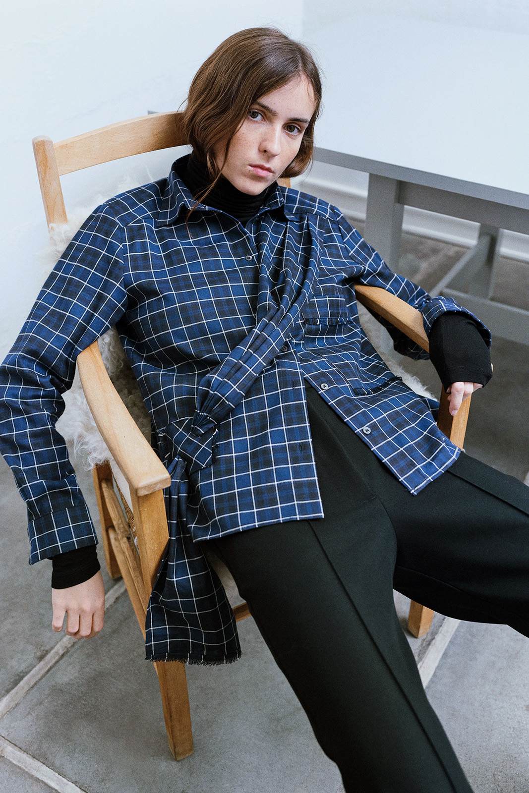 girl in a chair in a Checked navy shirt with a draped front tie detail