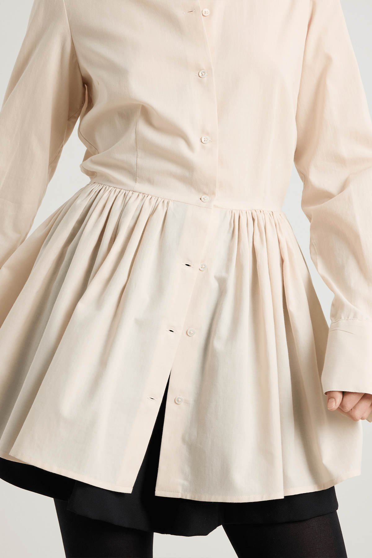 Cream long-sleeved mini dress with, button-down front, and gathered peplum-style skirt.