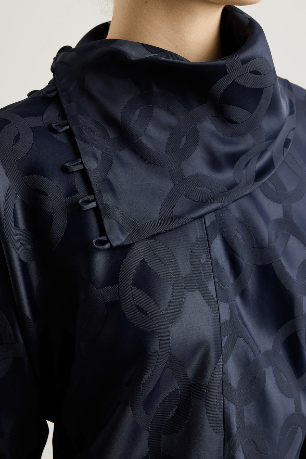 black top with subtle geometric jacquard pattern, and asymmetrical buttoned neckline