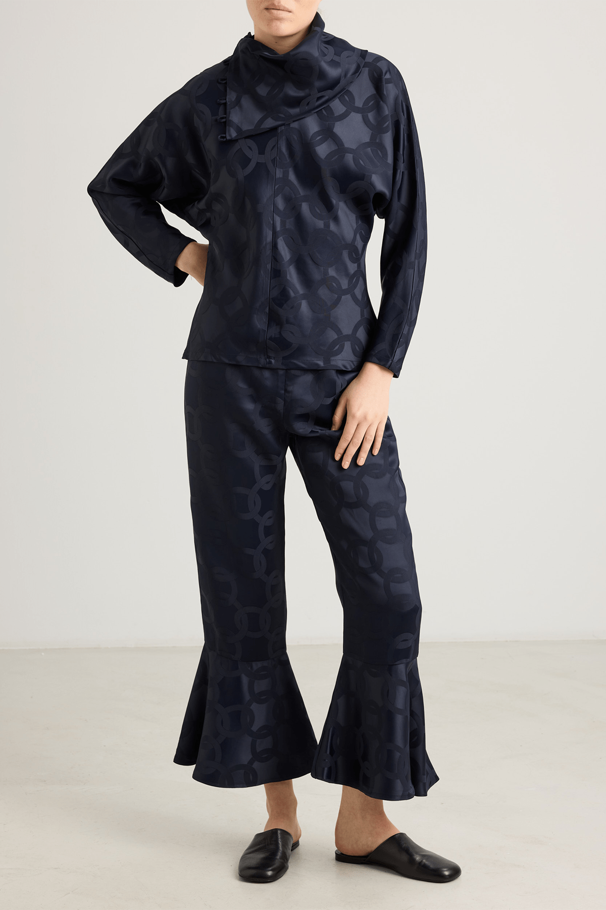 girl in black top with subtle geometric jacquard pattern, and asymmetrical buttoned neckline and long sleeves.