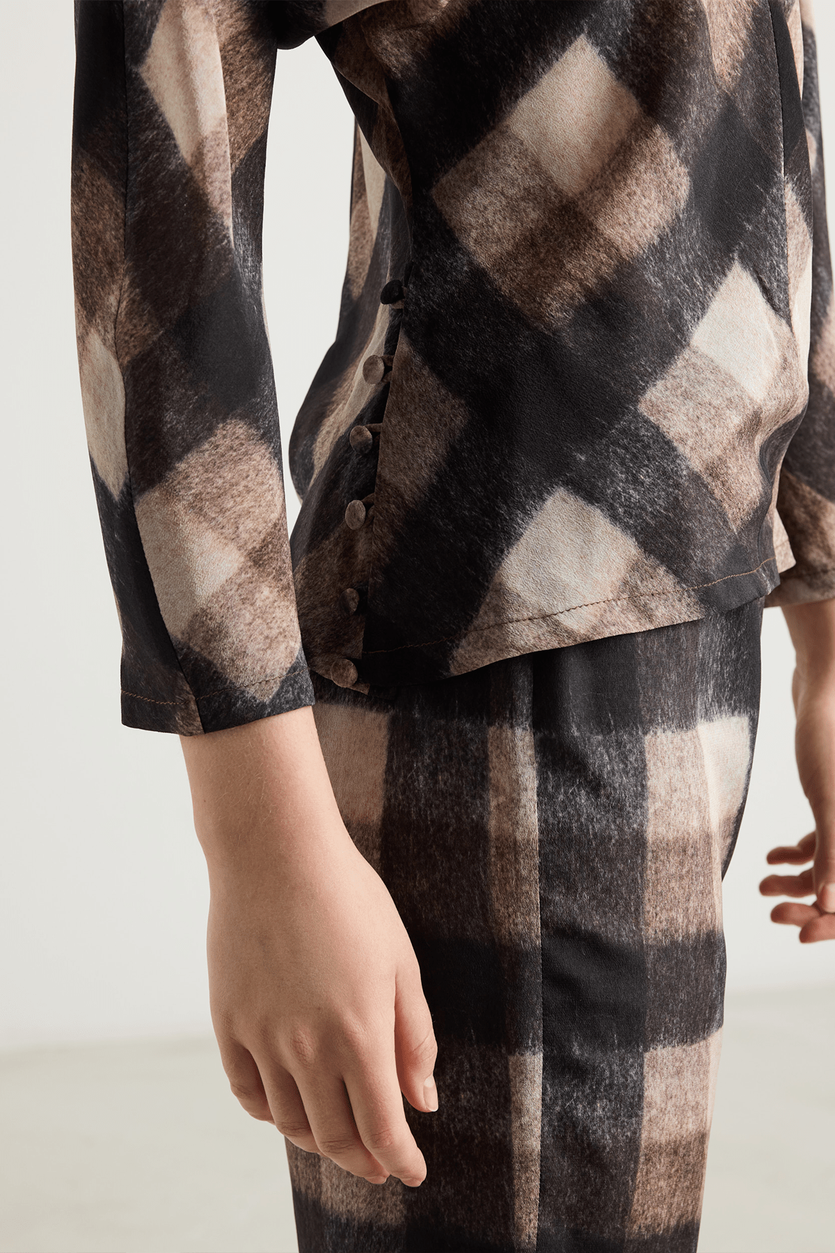 close op of Brown and black check top with button details and long sleeves.