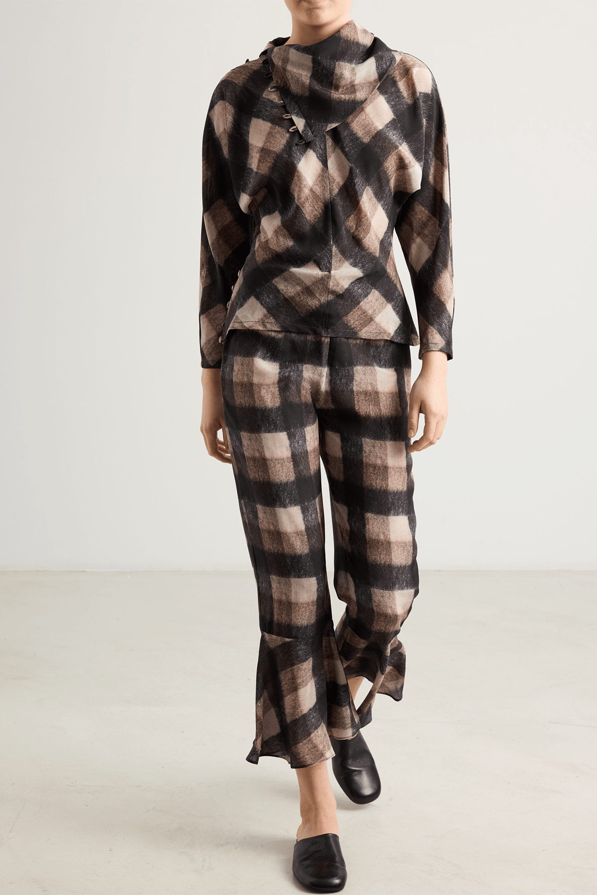 girl in Brown and black check top with asymmetrical buttoned neckline and long sleeves.