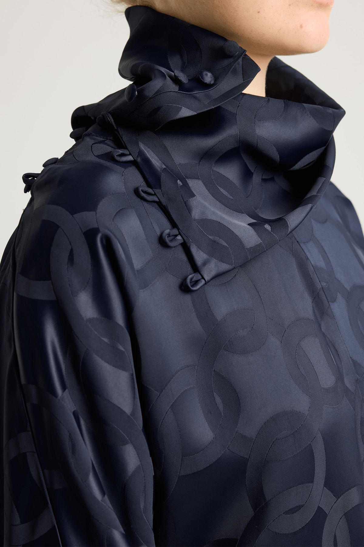 close up of an asymmetrical neckline in subtle geometric jacquard pattern.
