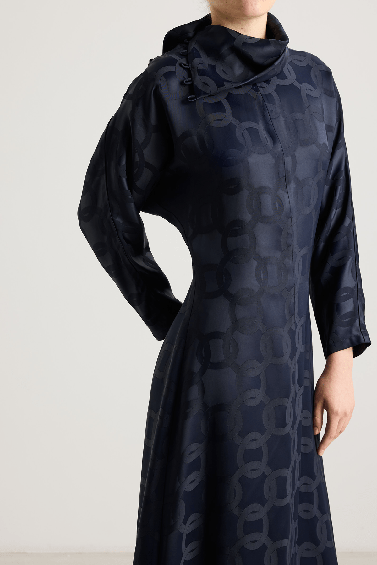 girl in black dress with an asymmetrical neckline and subtle geometric jacquard pattern.