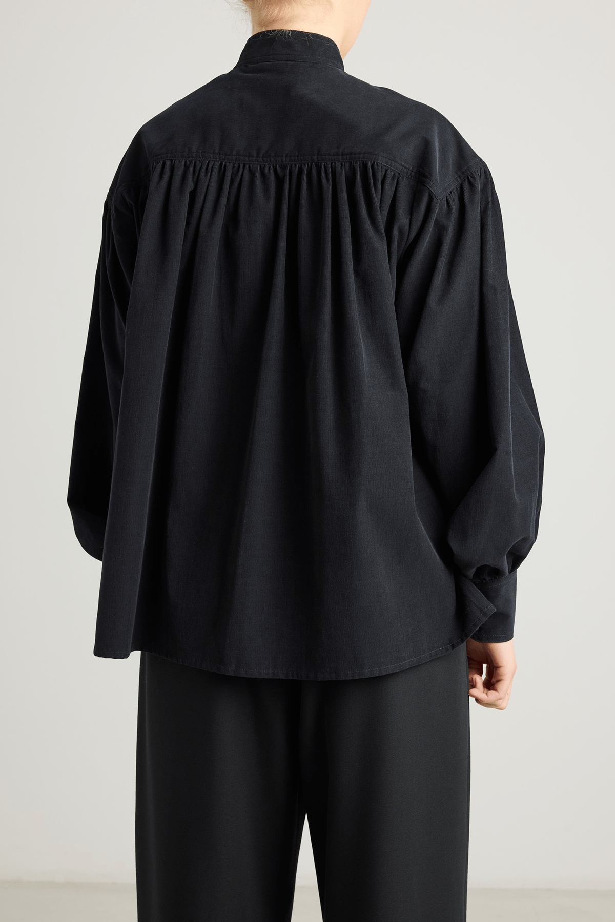 girl in black checked shirt with a tie-neck detail, front button closure, and long voluminous balloon sleeves gathered at the wrists.