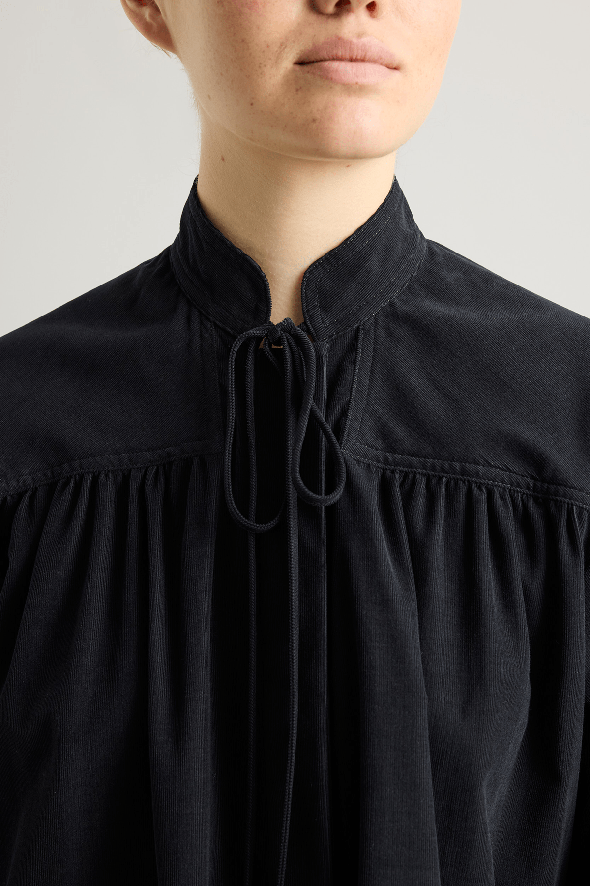 girl in black checked shirt with a tie-neck detail, front button closure