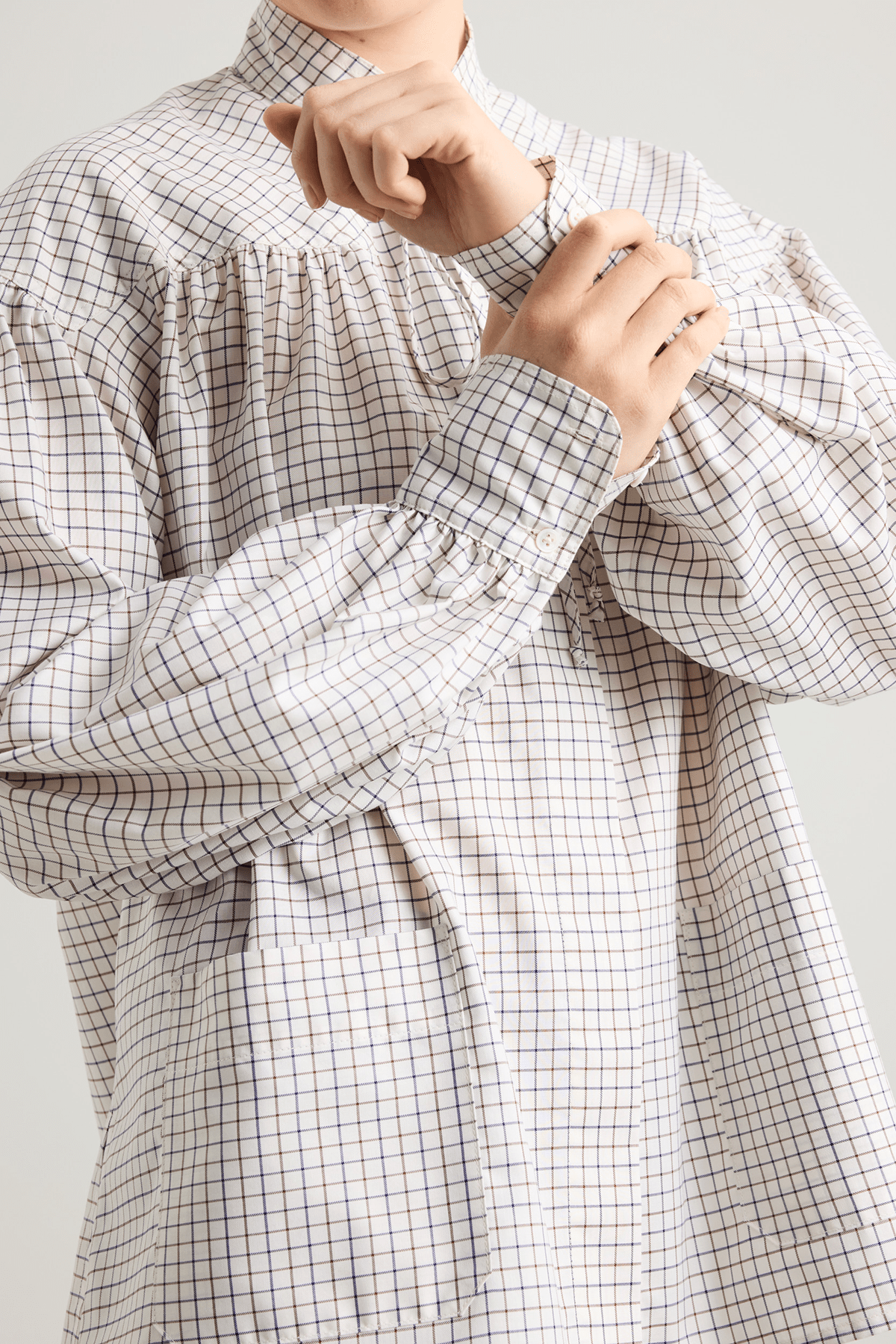 girl in White checked shirt with a tie-neck detail, front button closure, and long voluminous balloon sleeves gathered at the wrists.