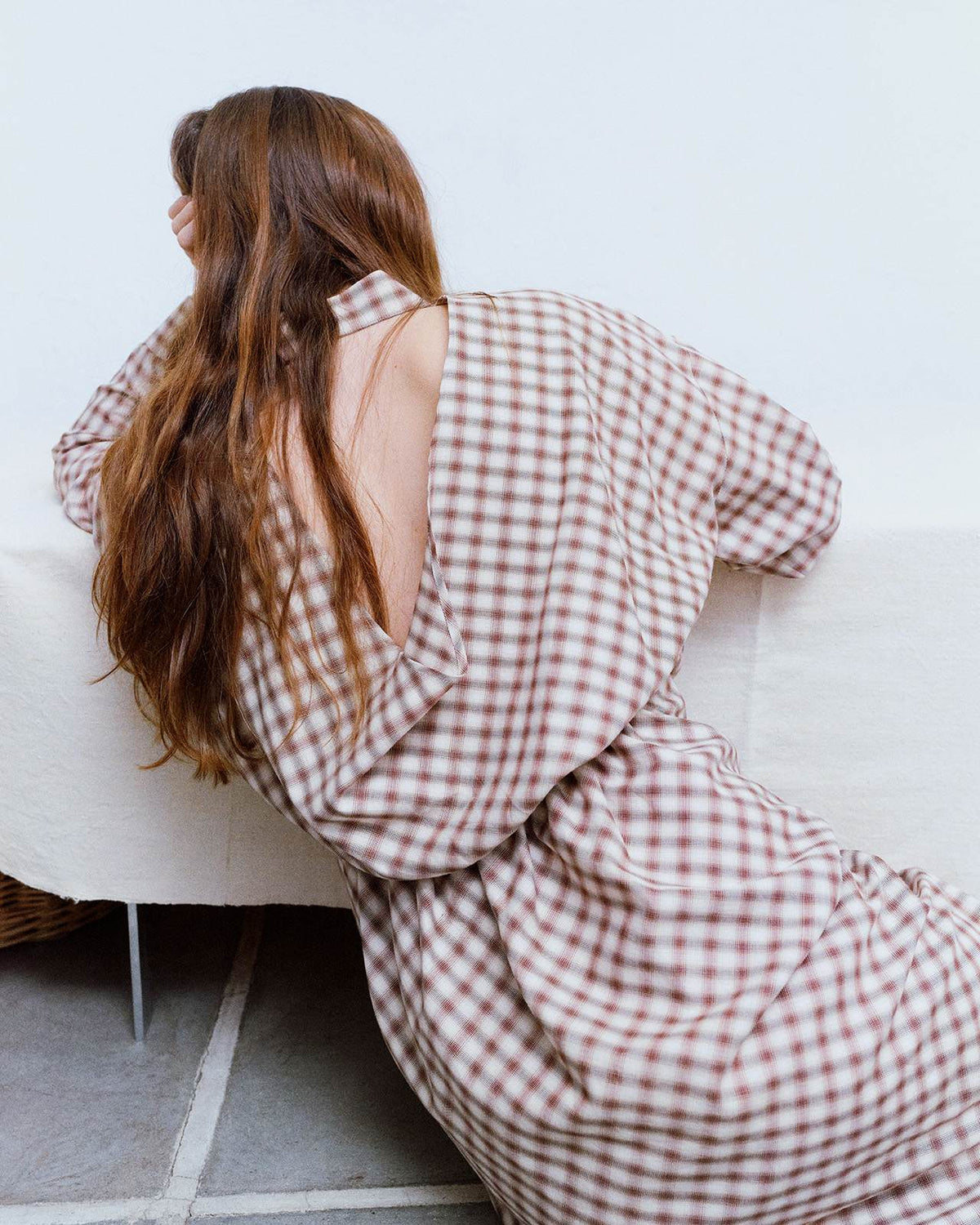 brunette girl on floor, with brown check dress with open back