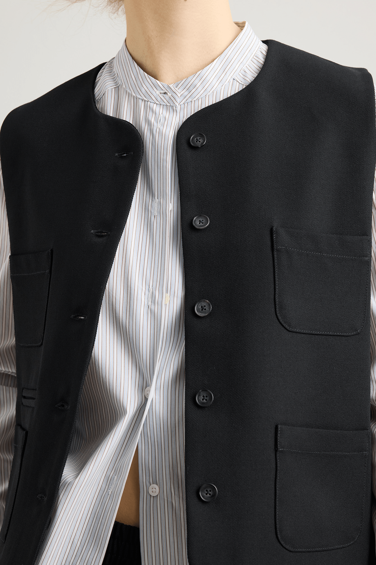 girl in black vest with four pockets and striped shirt