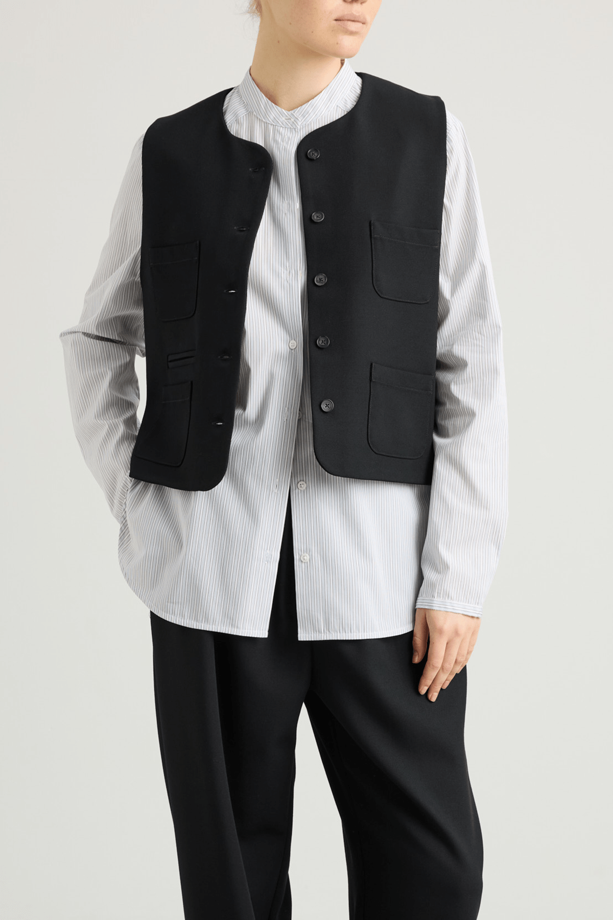 girl in black vest with four pockets and striped white shirt