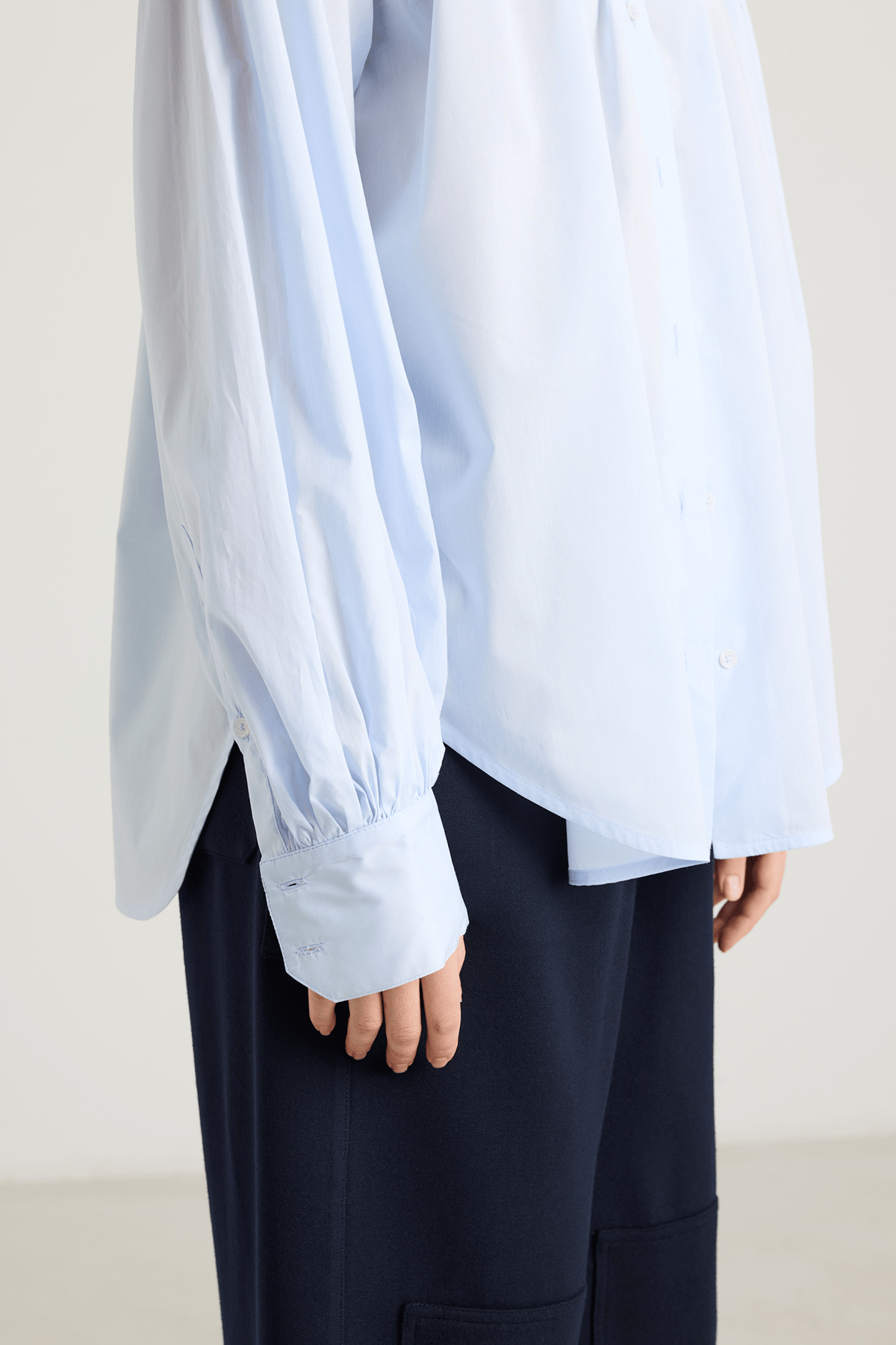 light blue blouse with front button closure, and long voluminous balloon sleeves gathered at the wrists.