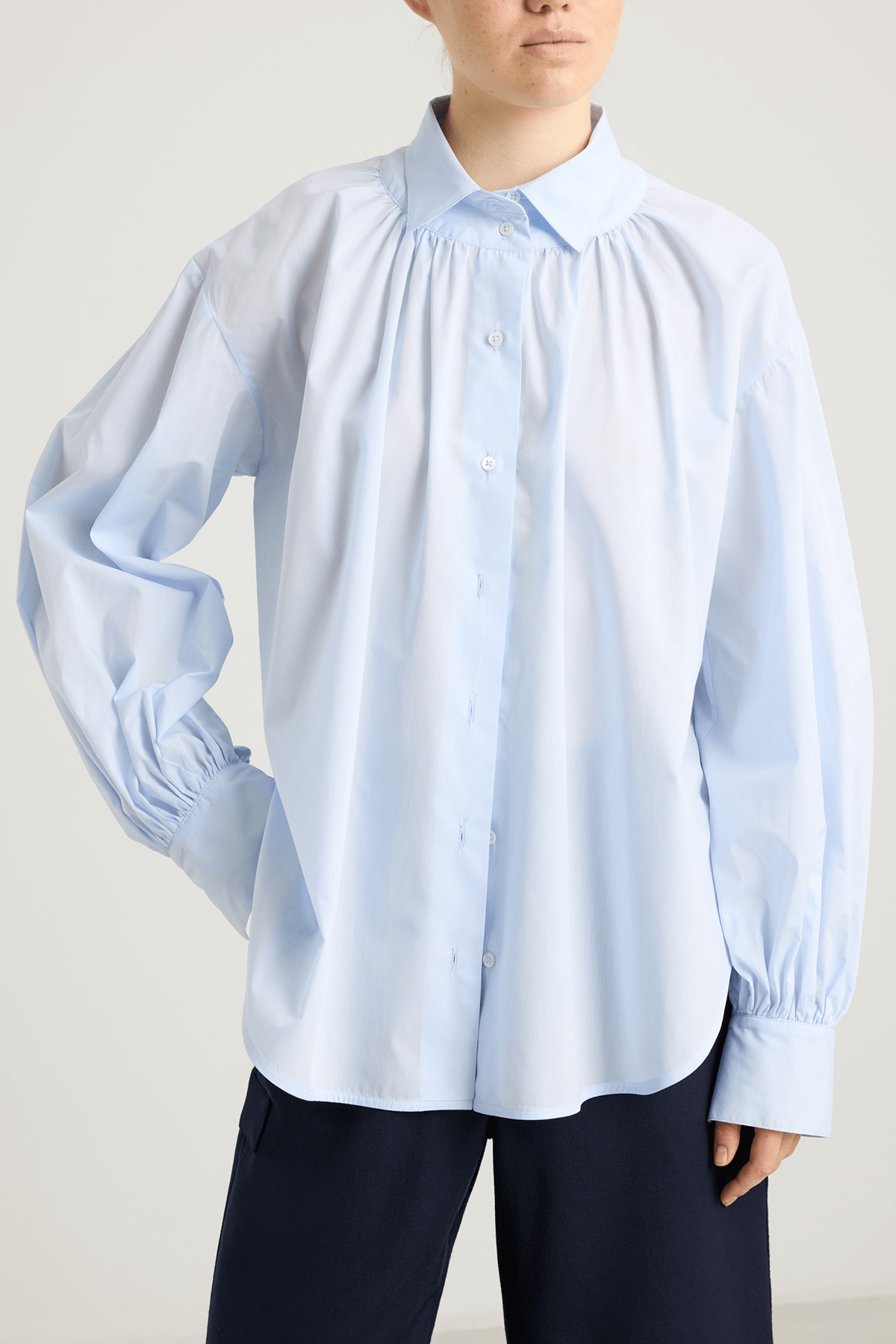 girl in light blue blouse with front button closure, and  balloon sleeves gathered at the wrists.