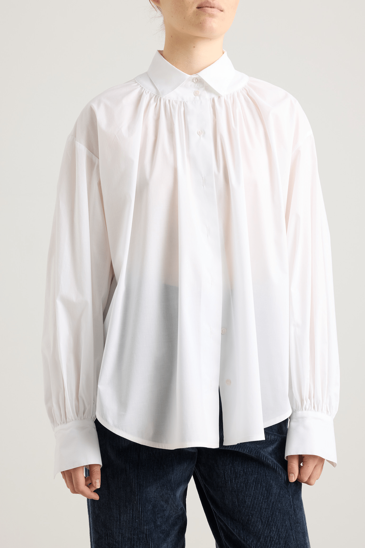 White blouse with front button closure, and long voluminous balloon sleeves gathered at the wrists.