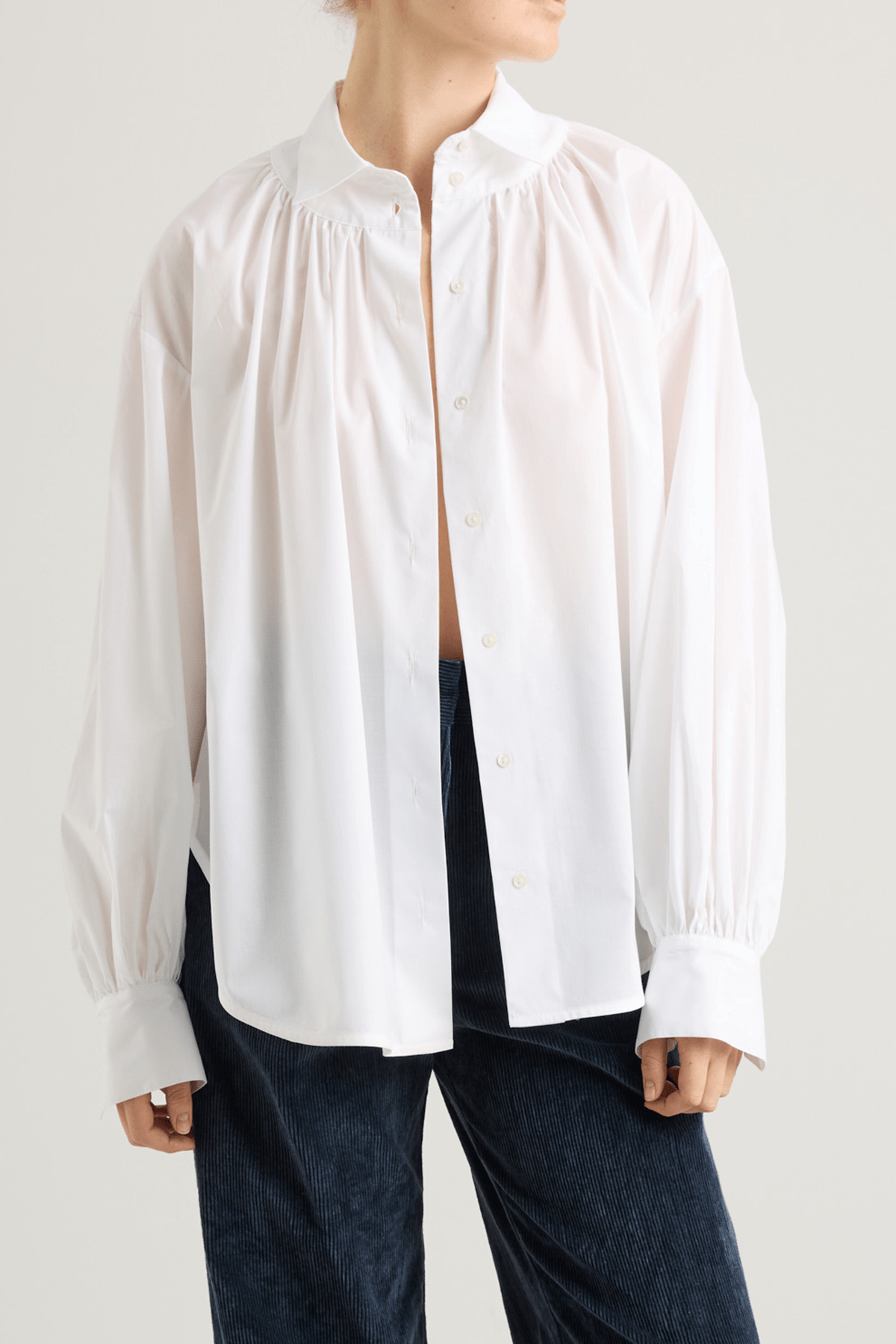 girl in White blouse with front button closure, and long voluminous balloon sleeves gathered at the wrists.