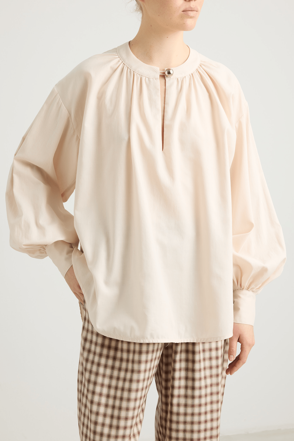 girl in cream colored blouse and checked trousers